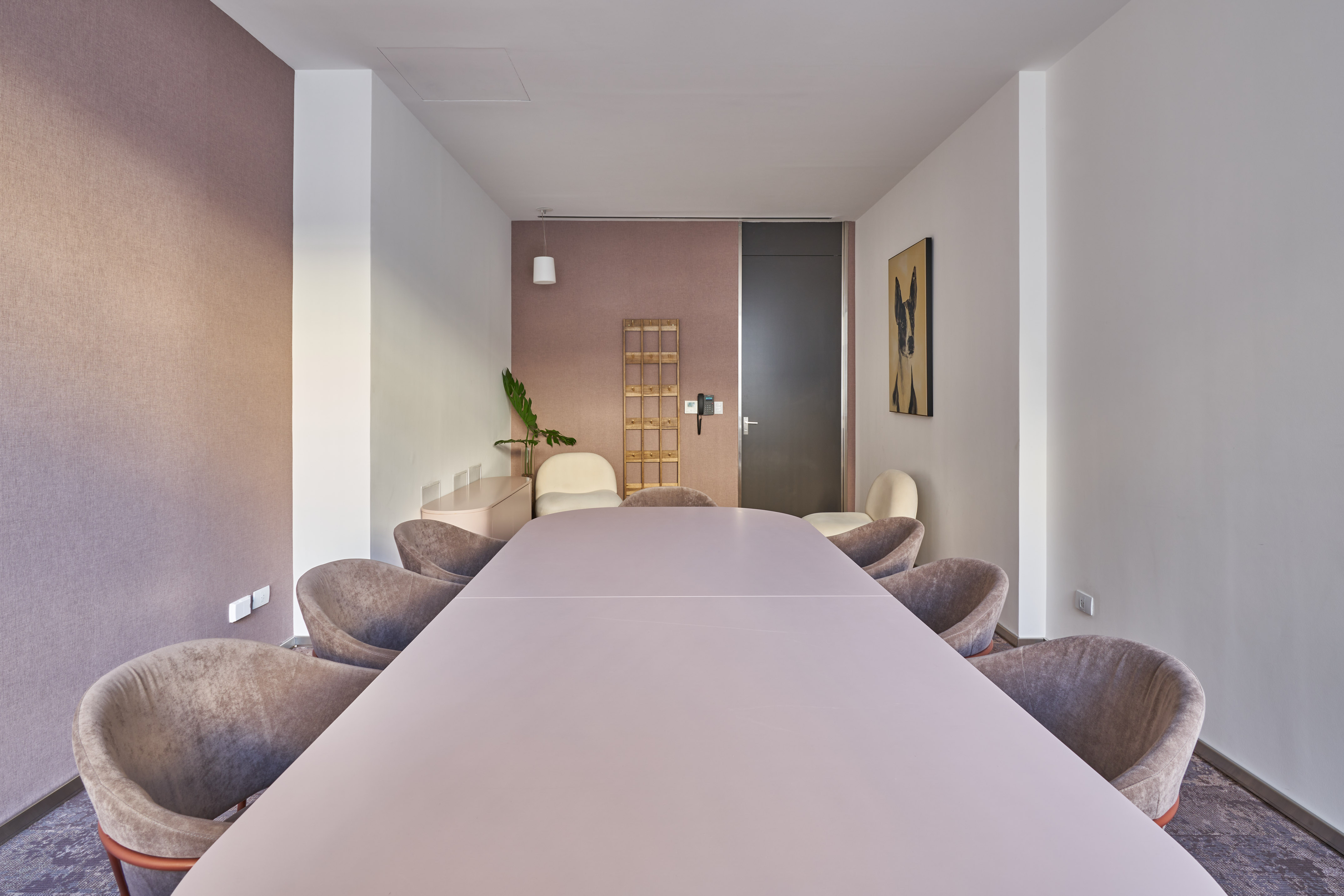 Contemporary meeting room with light pink table, gray chairs, and accent wall.