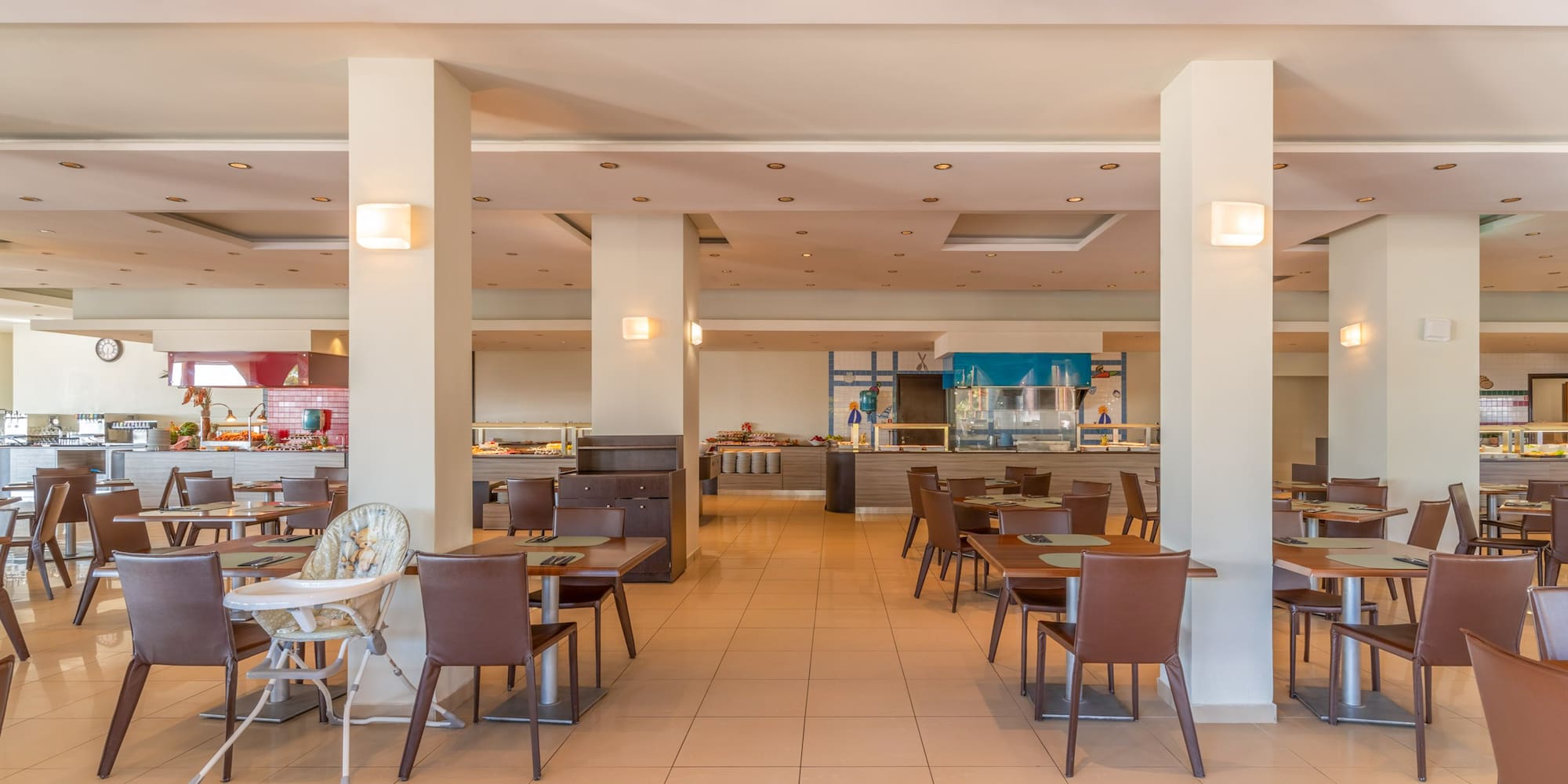 Spacious hotel restaurant buffet with dining tables and baby high chair.