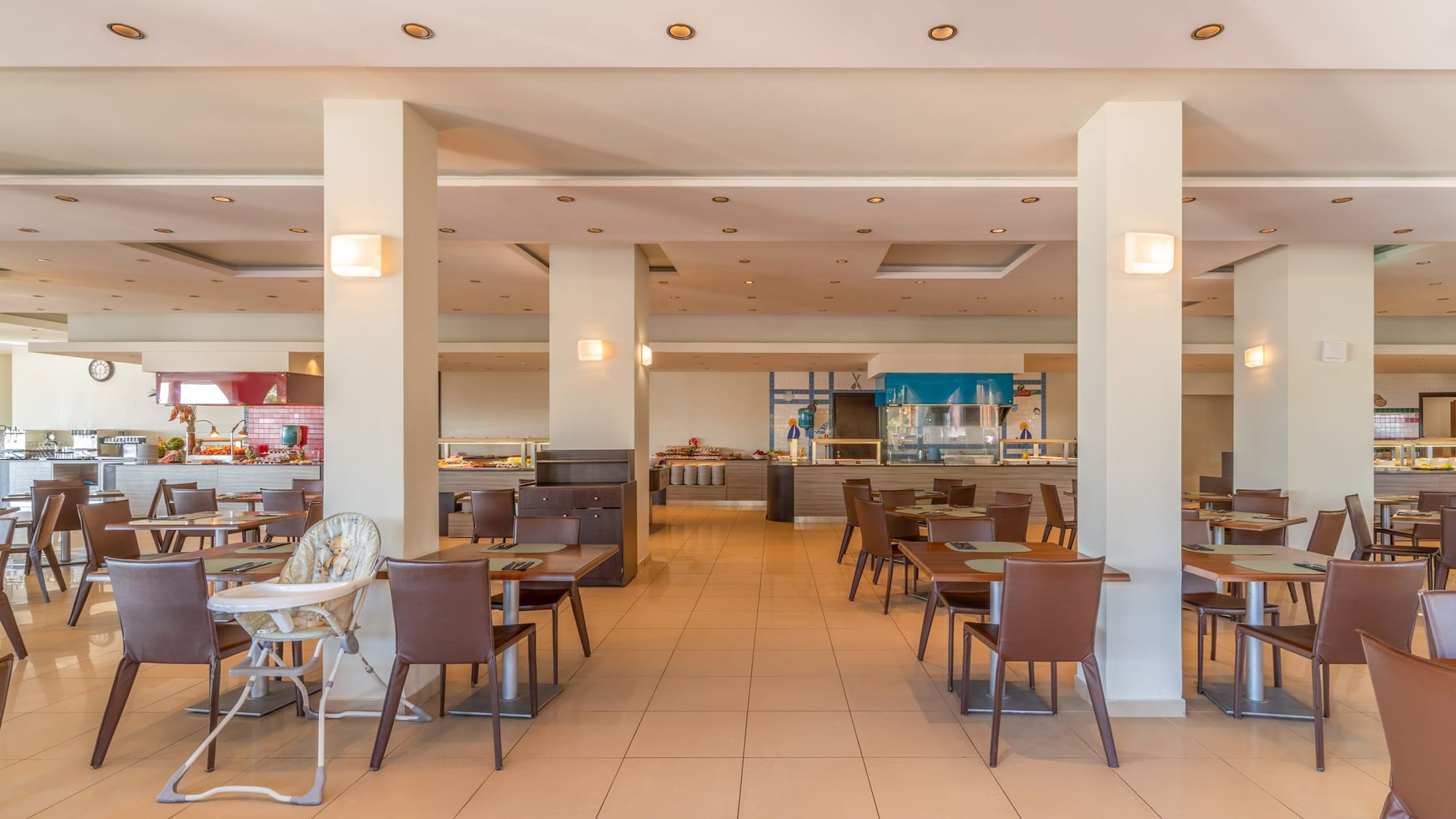 Spacious hotel restaurant buffet with dining tables and baby high chair.