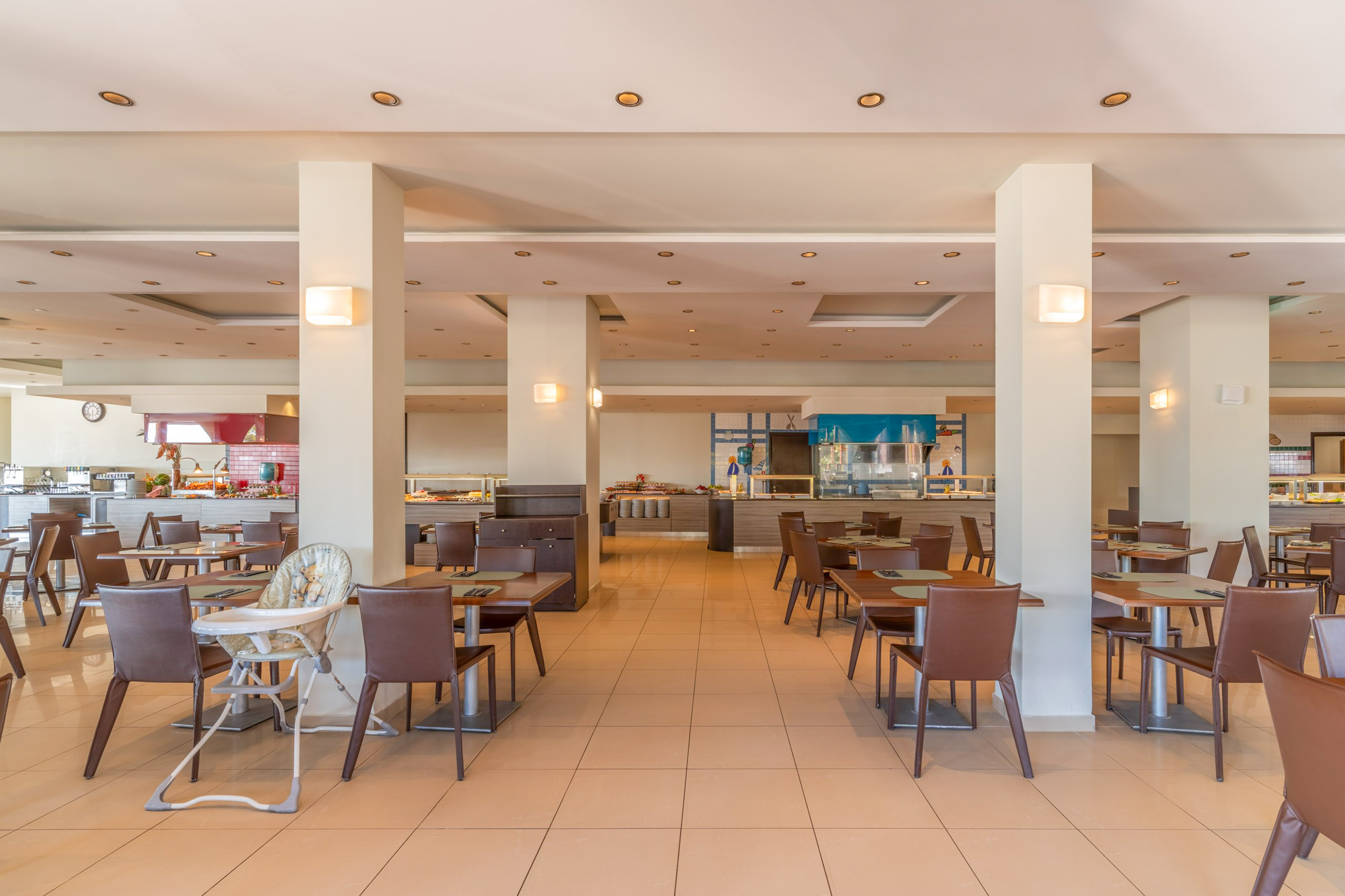 Spacious hotel restaurant buffet with dining tables and baby high chair.
