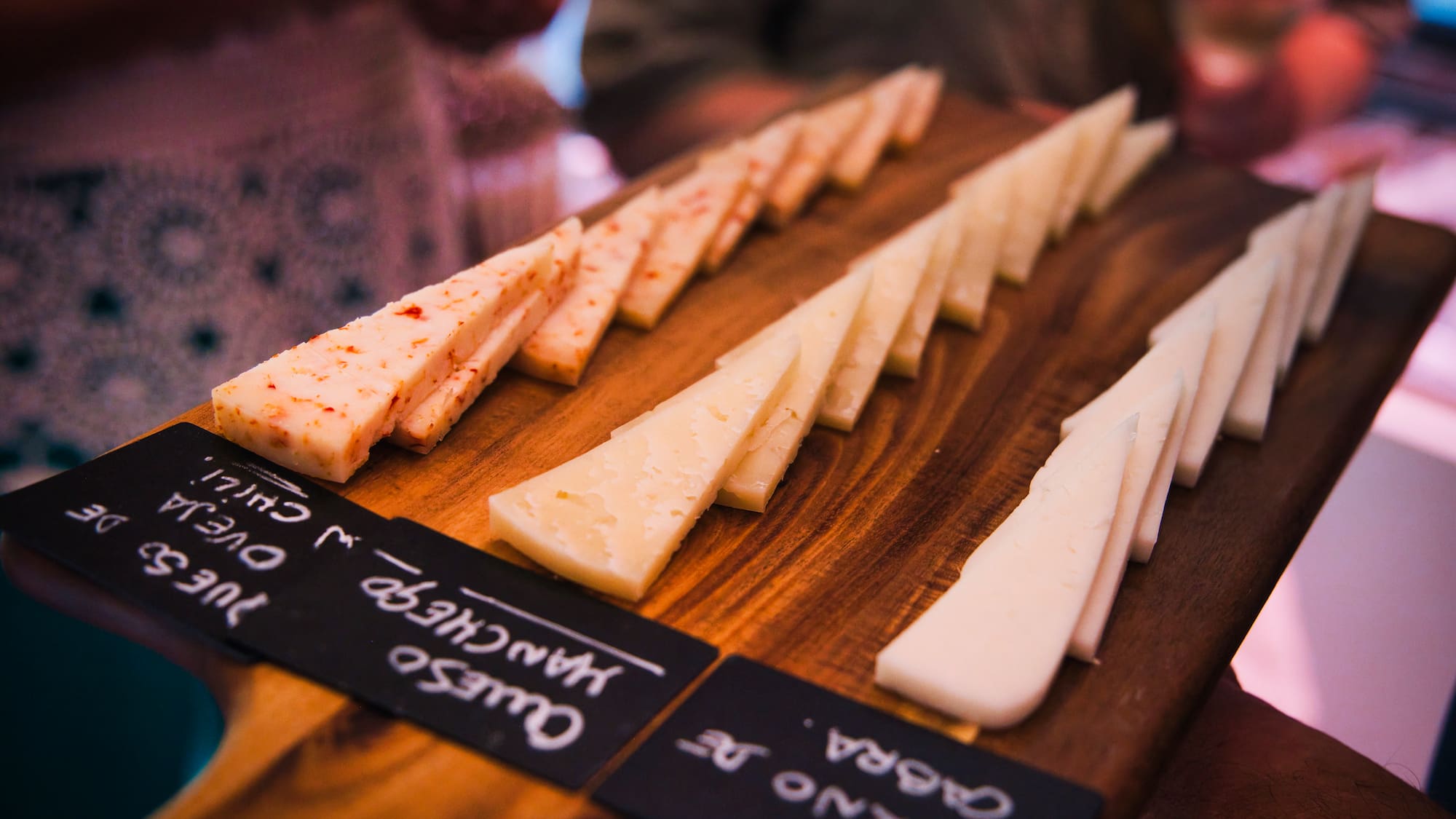 Sliced Spanish cheese board with Manchego, goat, and chili cheese varieties.