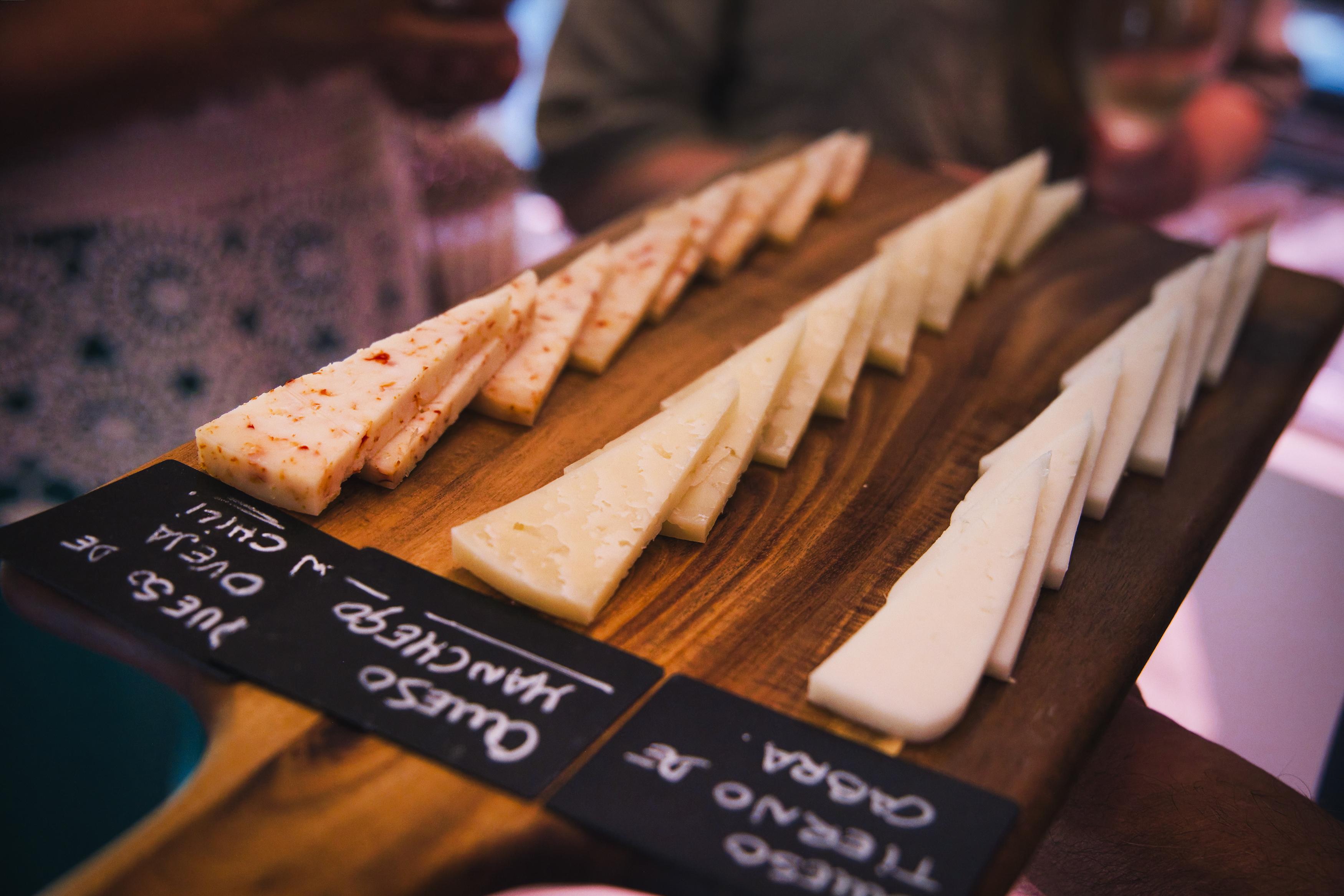 Sliced Spanish cheese board with Manchego, goat, and chili cheese varieties.