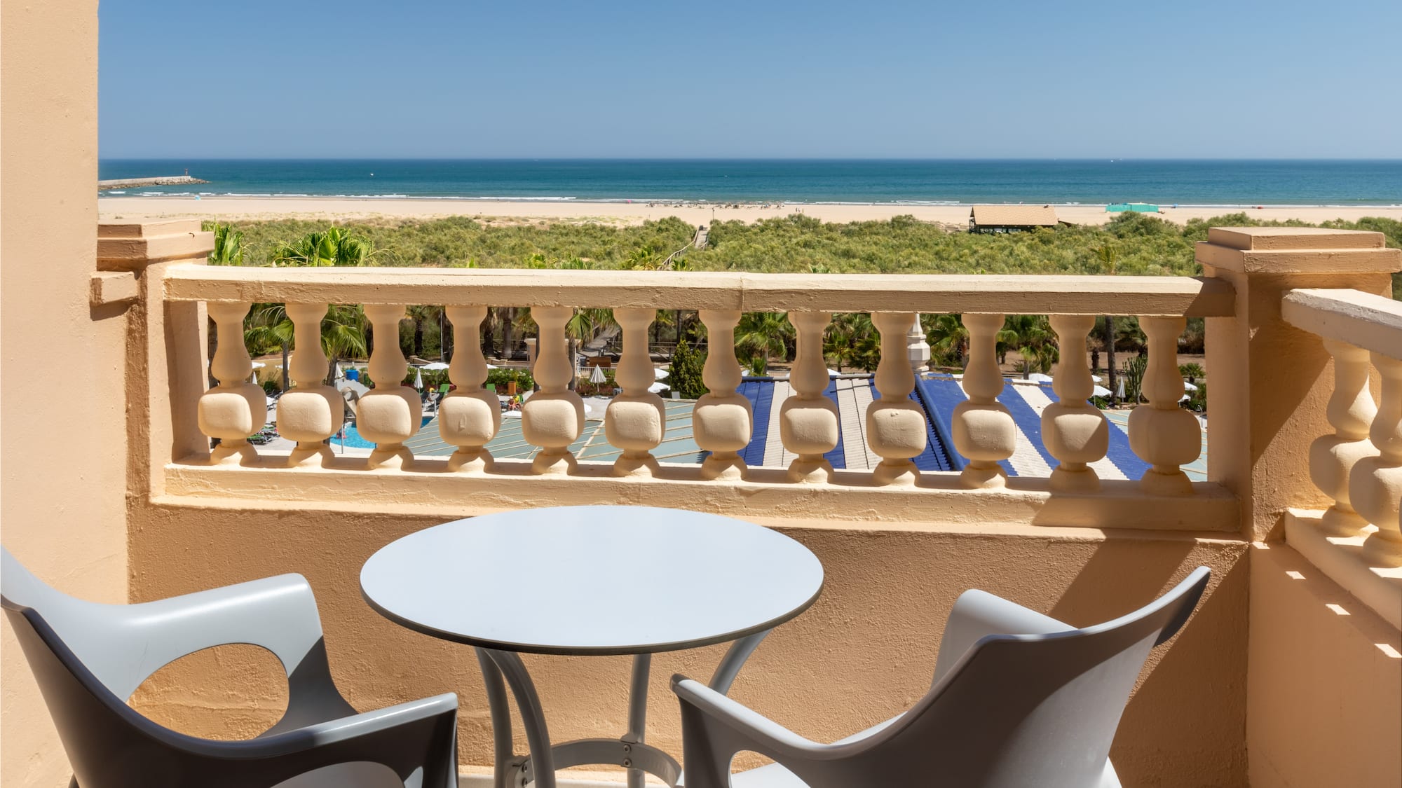 a table and chairs on a balcony overlooking a beach