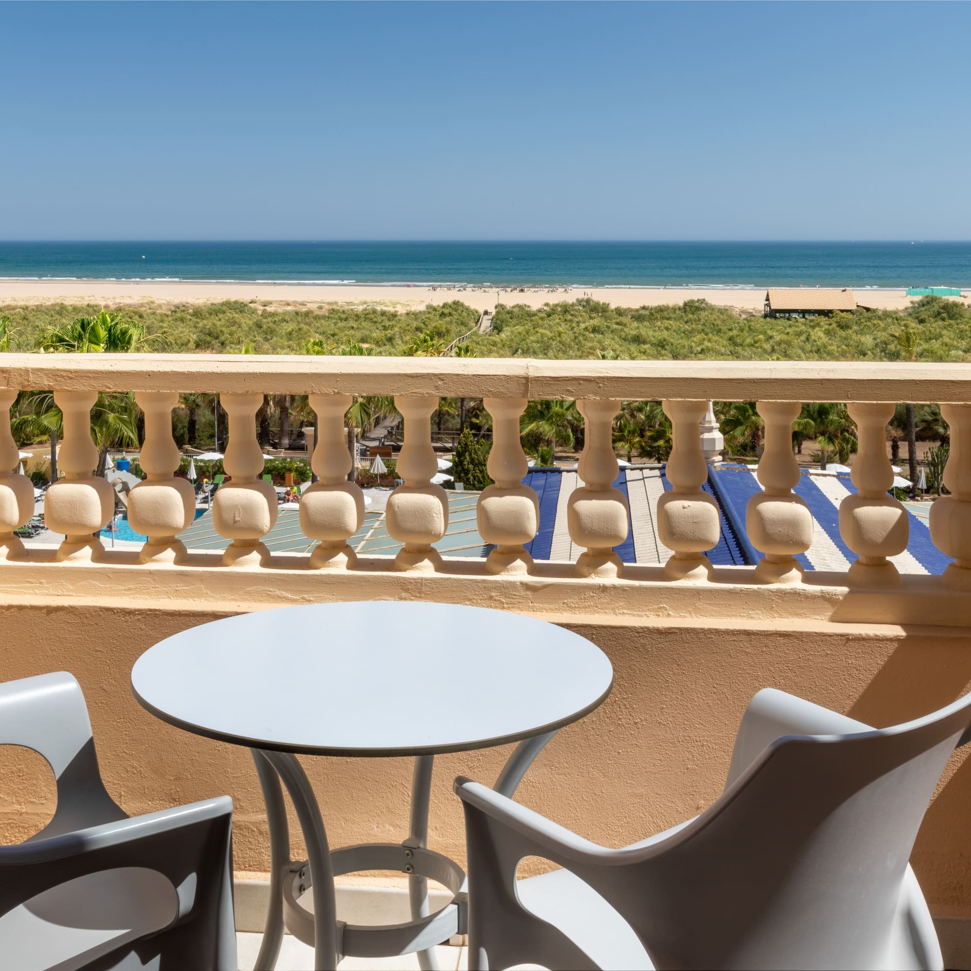 a table and chairs on a balcony overlooking a beach