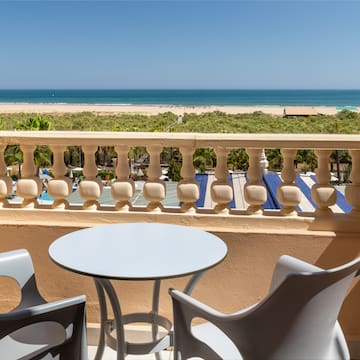 a table and chairs on a balcony overlooking a beach