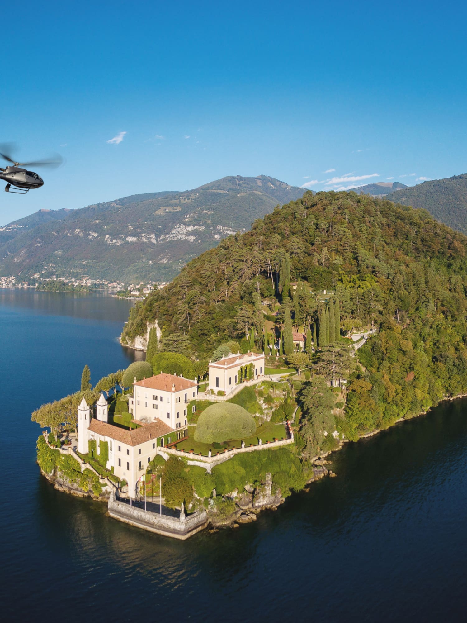Helicopter flying over luxury villa on Lake Como peninsula.