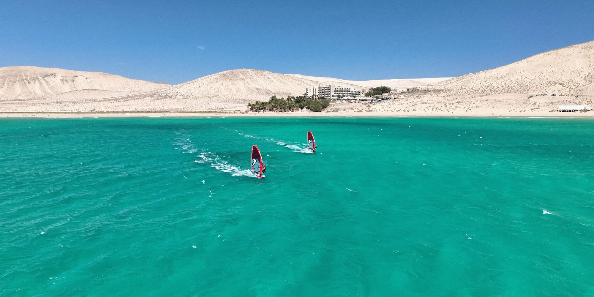 a pair of windsurfers in the water