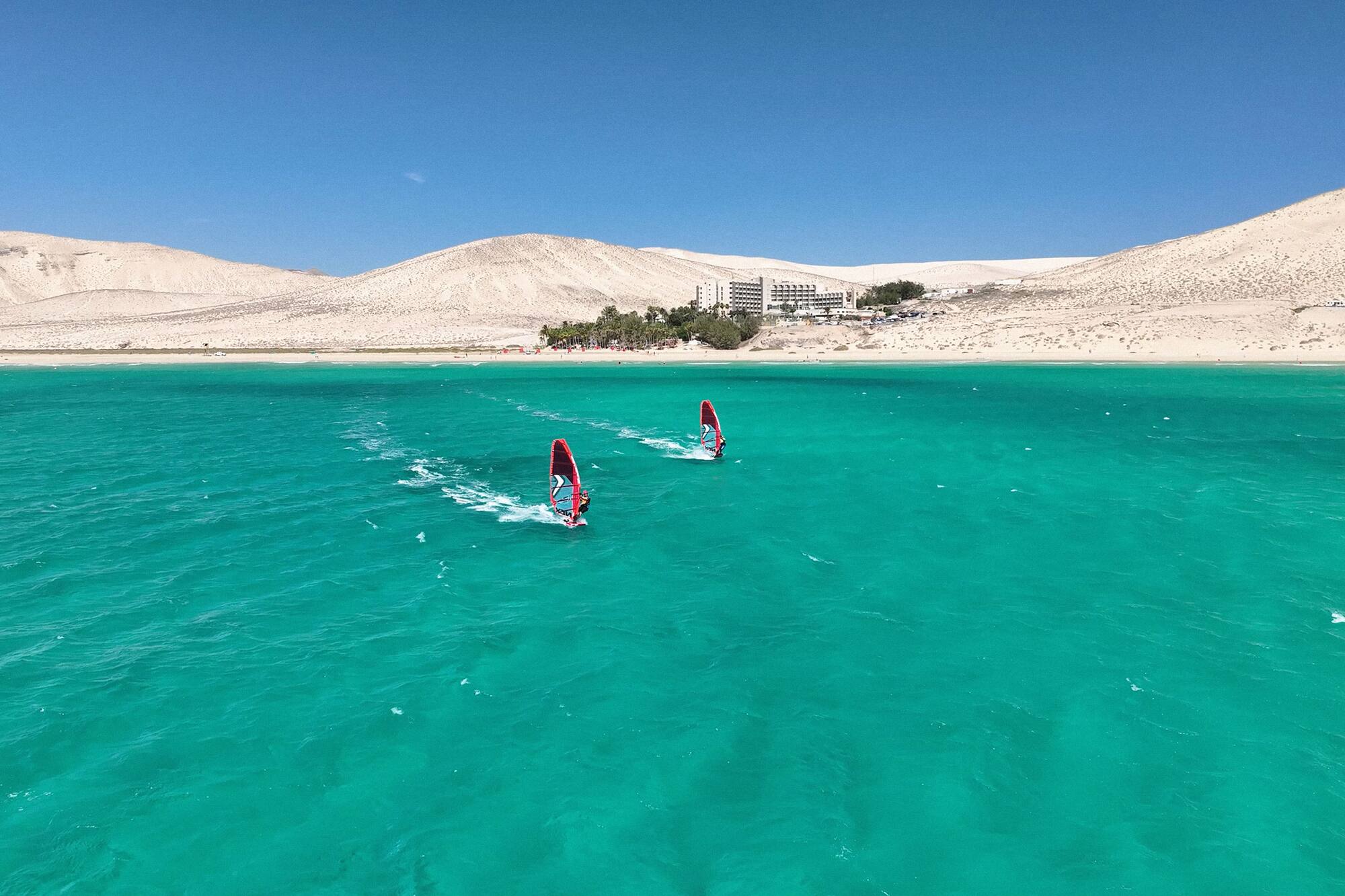 a pair of windsurfers in the water