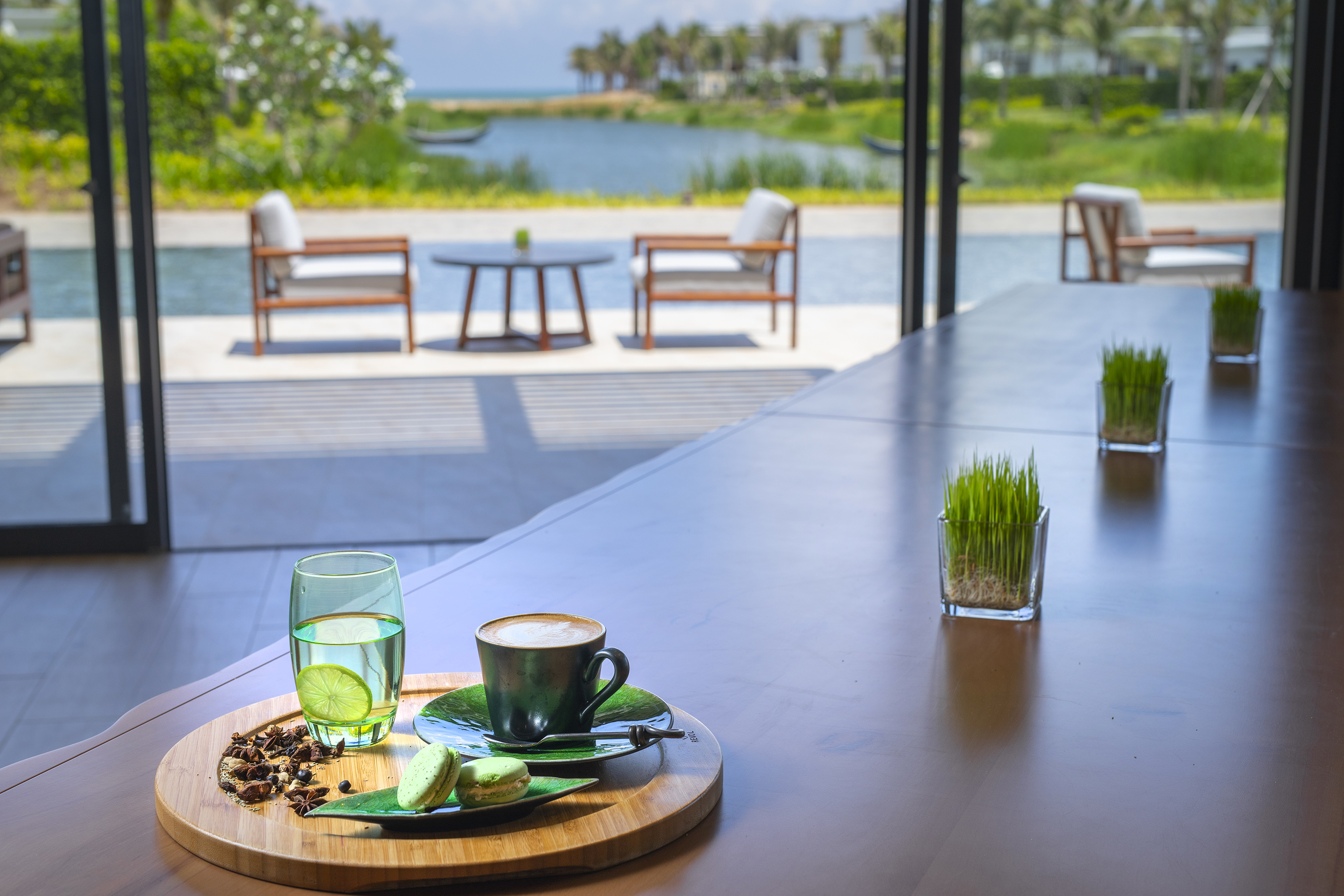 Coffee and macarons on a resort lounge table with scenic lake view.