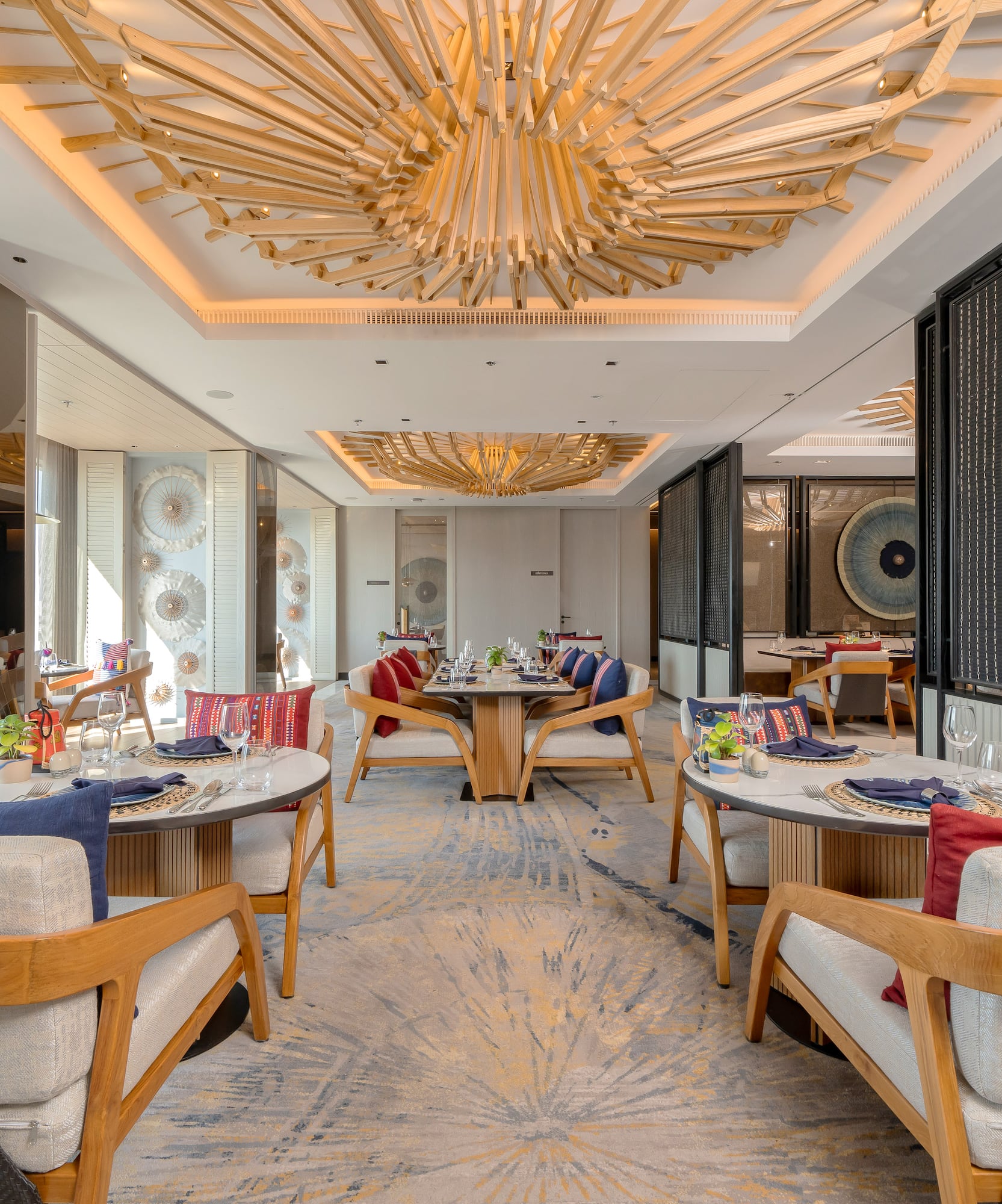 Elegant dining room with sculptural wooden ceiling and stylish table settings.