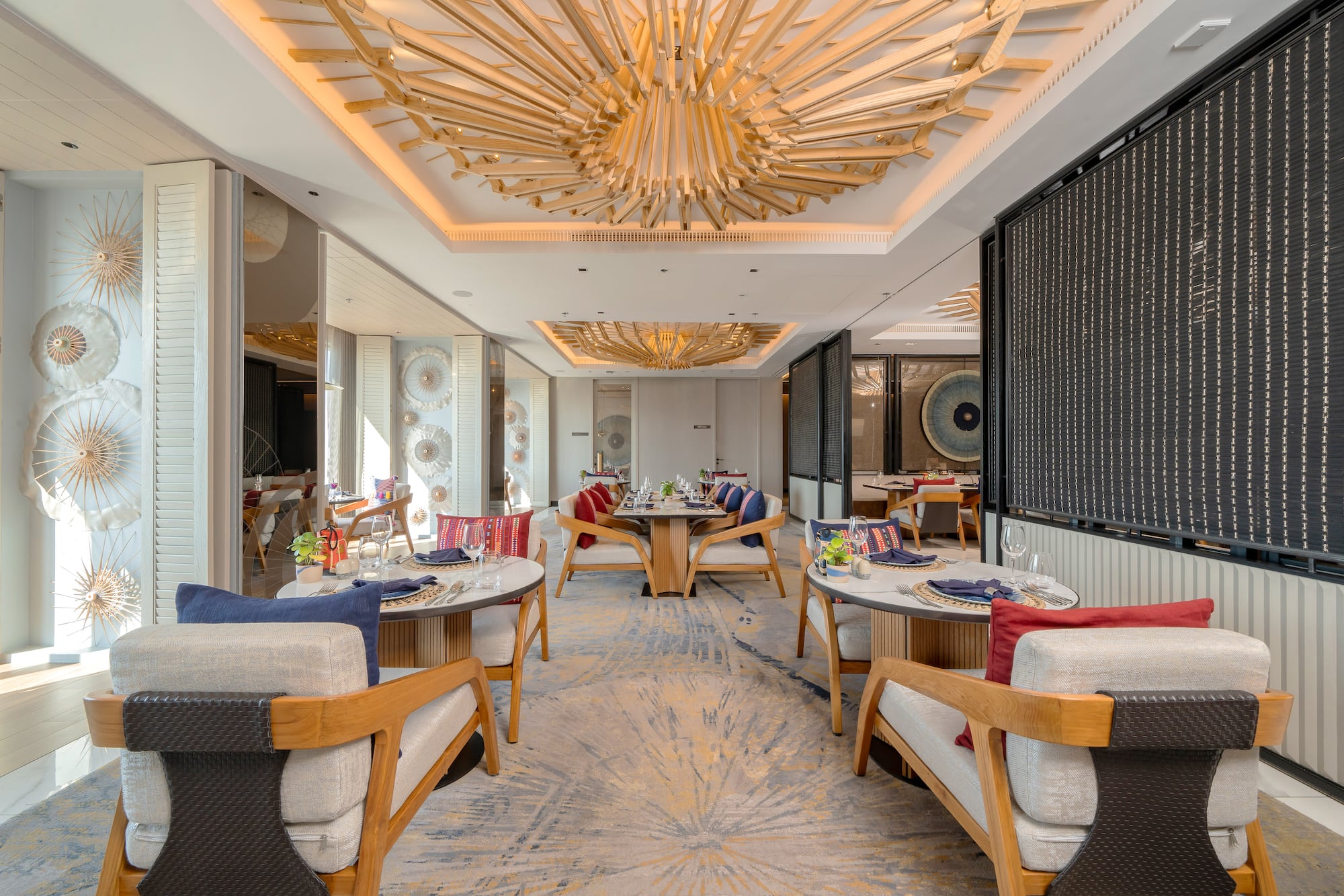 Elegant dining room with sculptural wooden ceiling and stylish table settings.