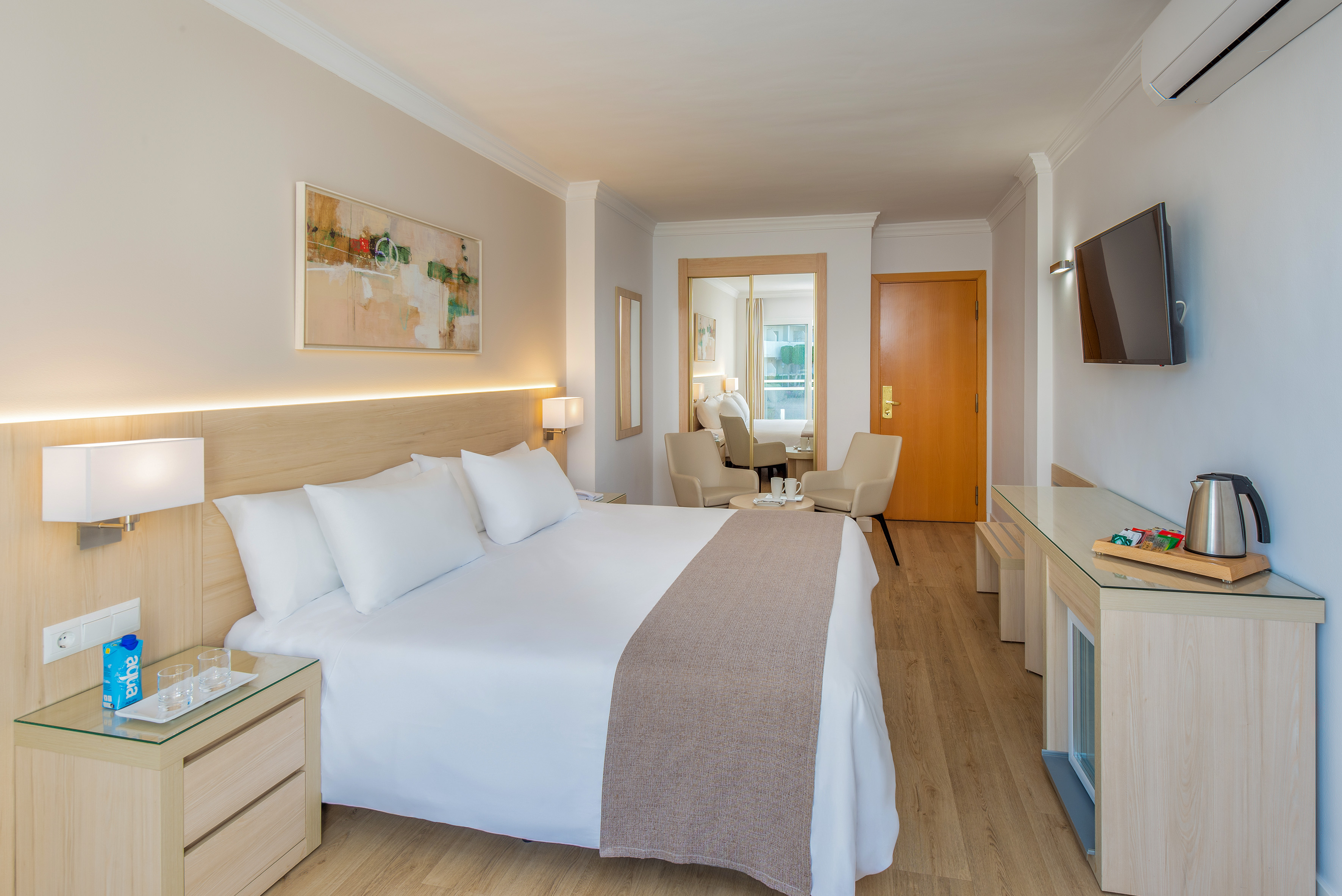 Comfortable hotel bedroom with large bed, seating, and modern amenities.
