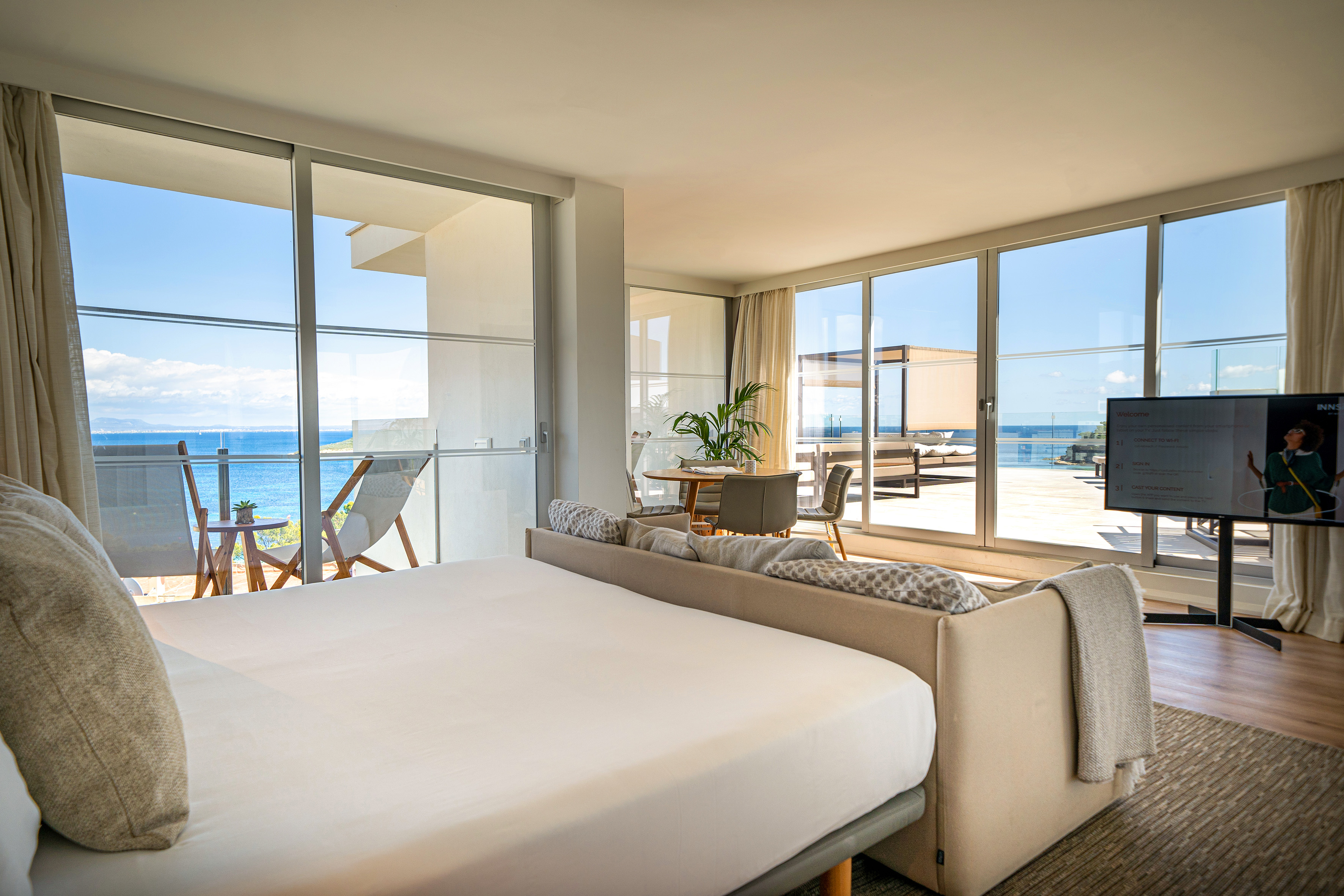Luxury hotel suite with sea view, modern bedroom, and outdoor terrace.