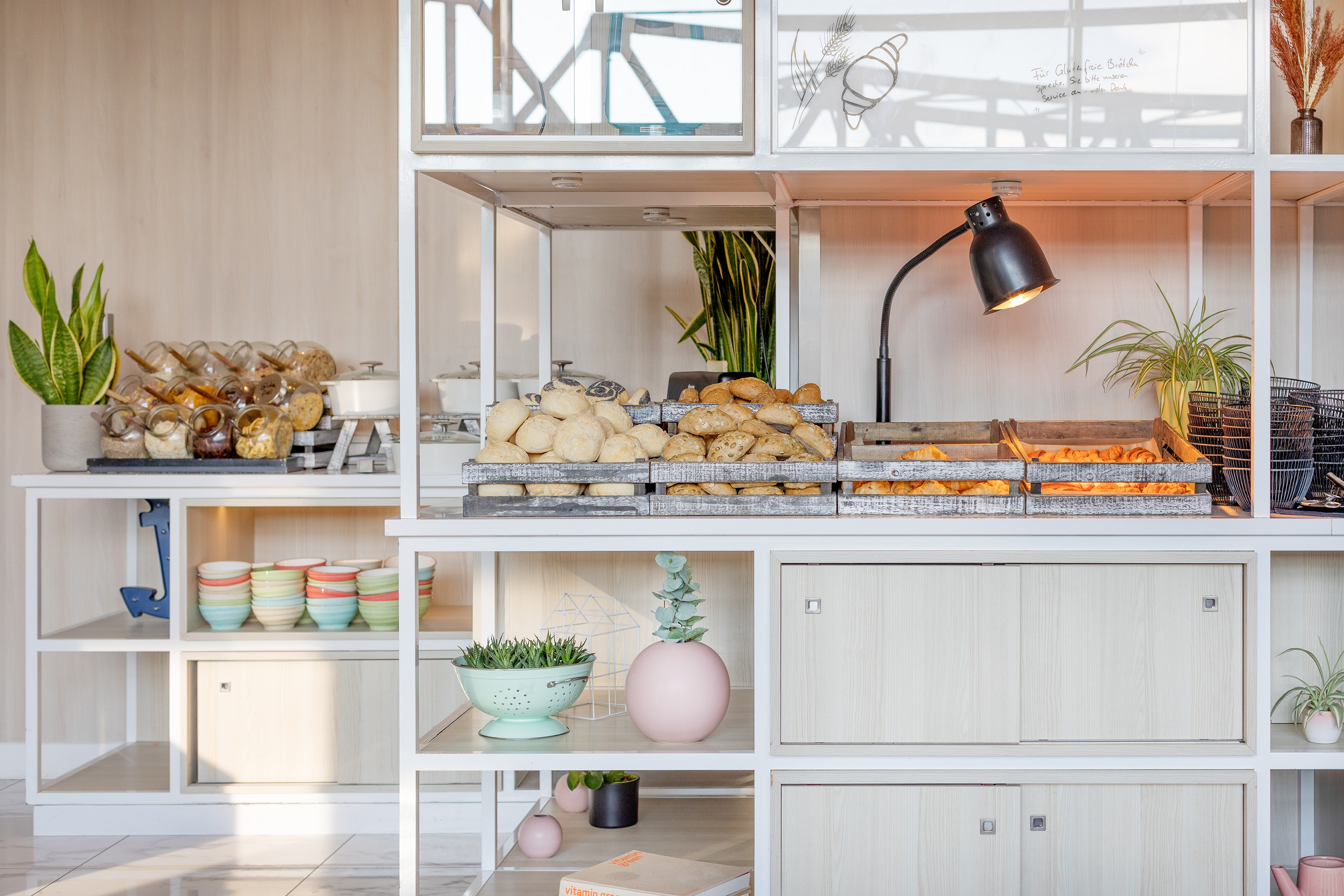 Modern breakfast buffet with fresh baked goods, cereals, and elegant decor.