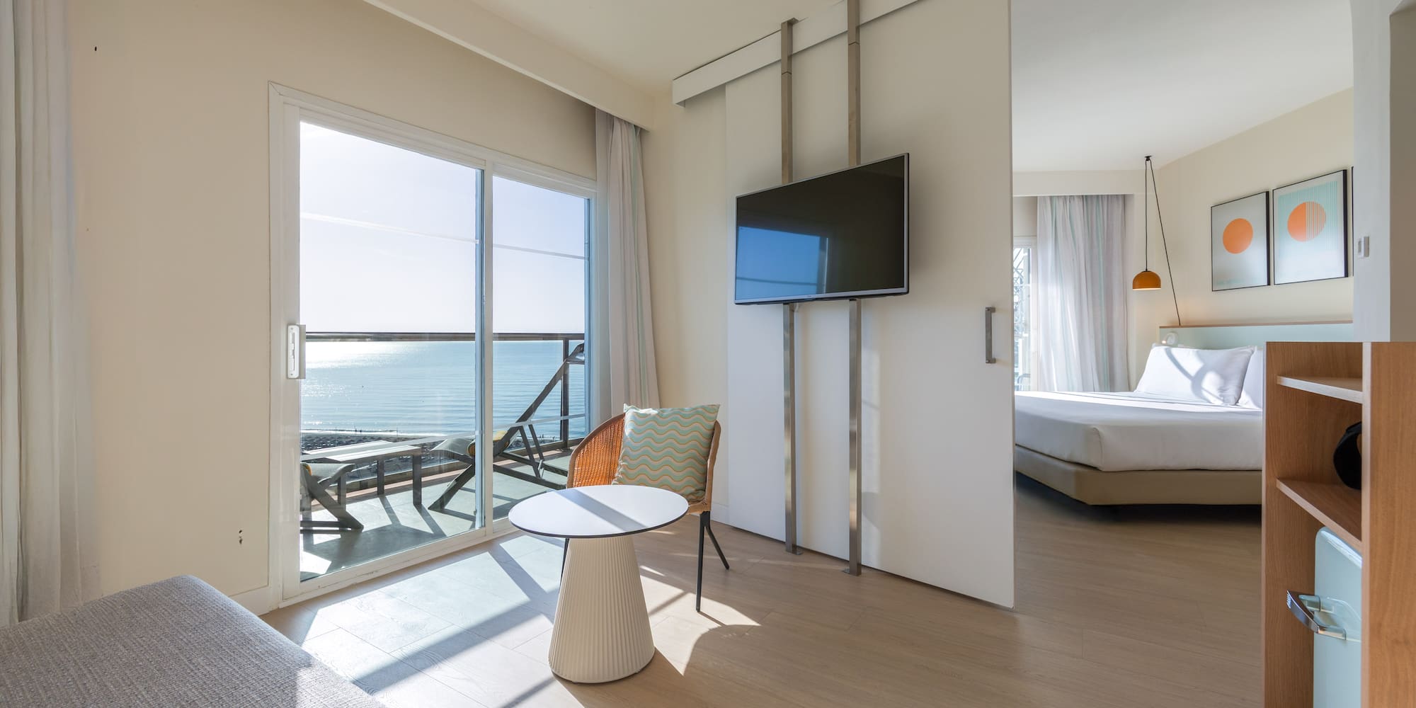 Bright hotel suite with ocean view balcony and sliding door to bedroom.