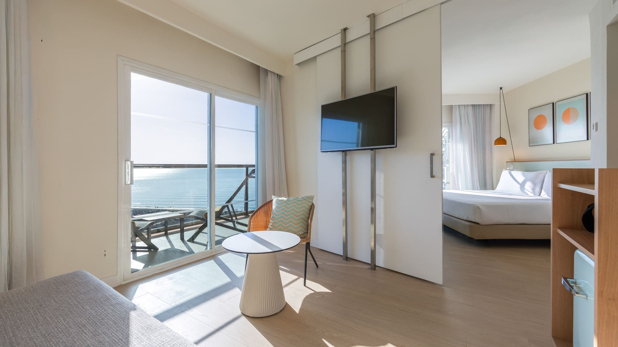 Bright hotel suite with ocean view balcony and sliding door to bedroom.
