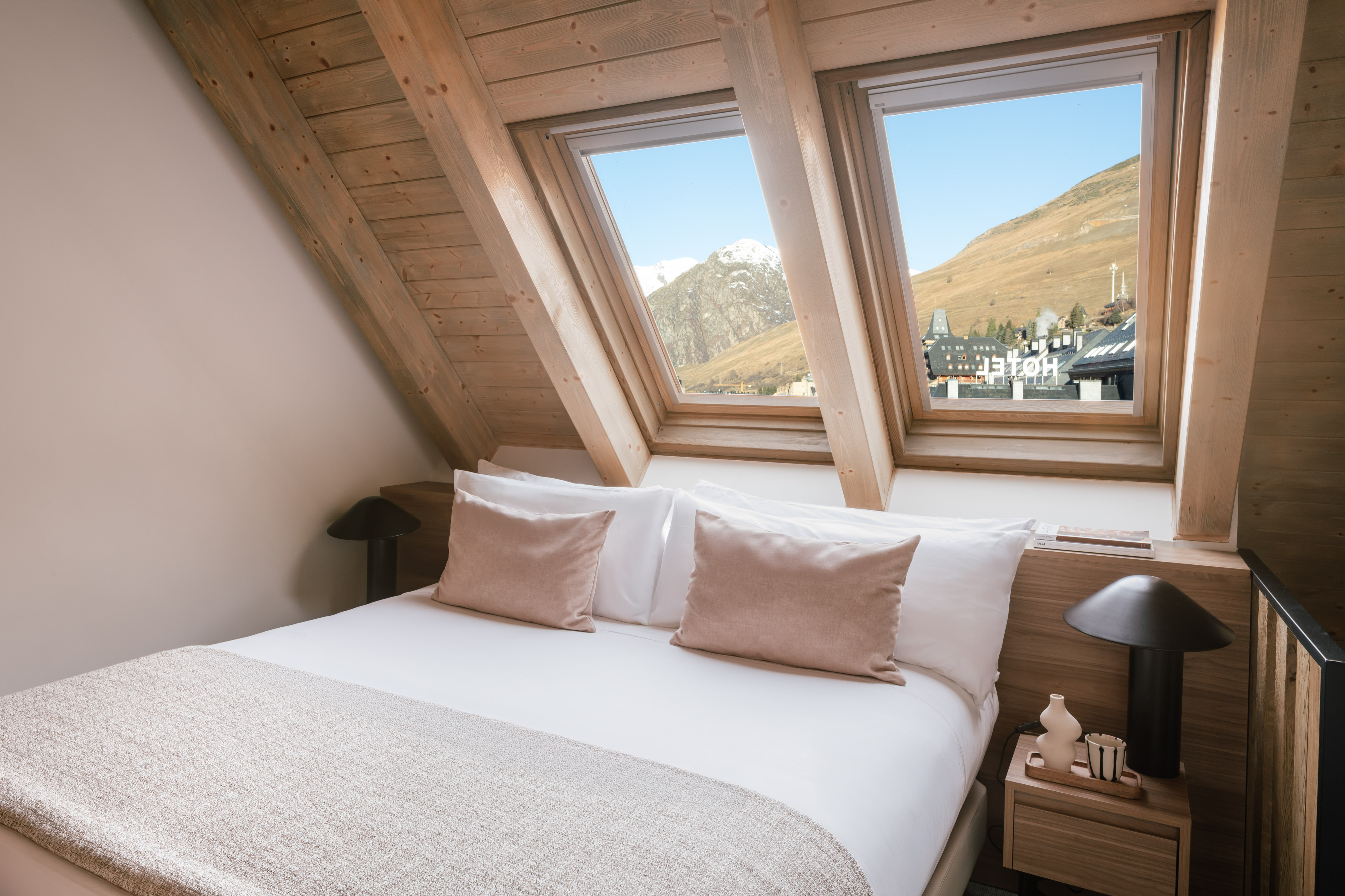 Ski resort hotel bedroom with mountain view through skylight windows.