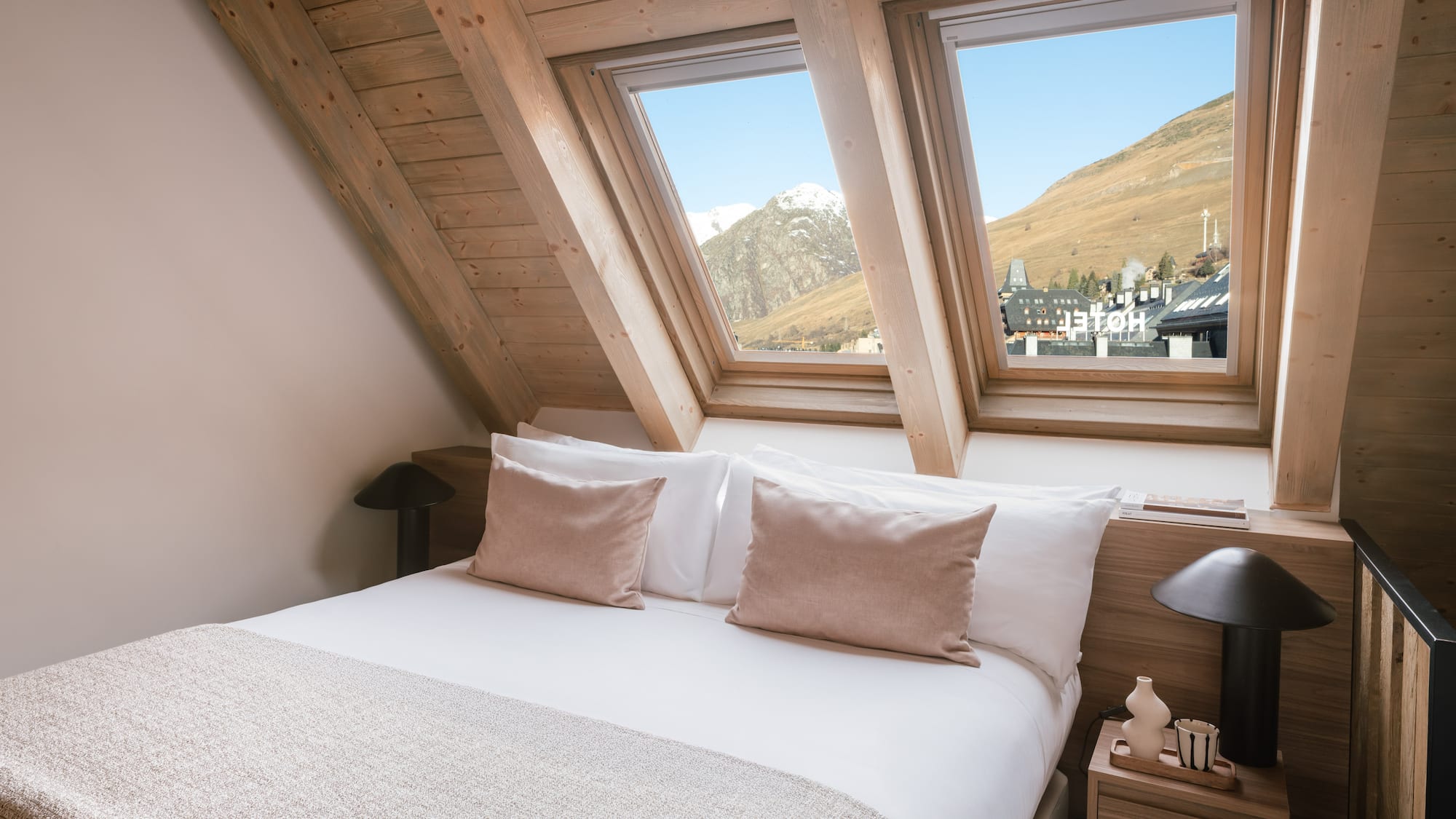 Ski resort hotel bedroom with mountain view through skylight windows.