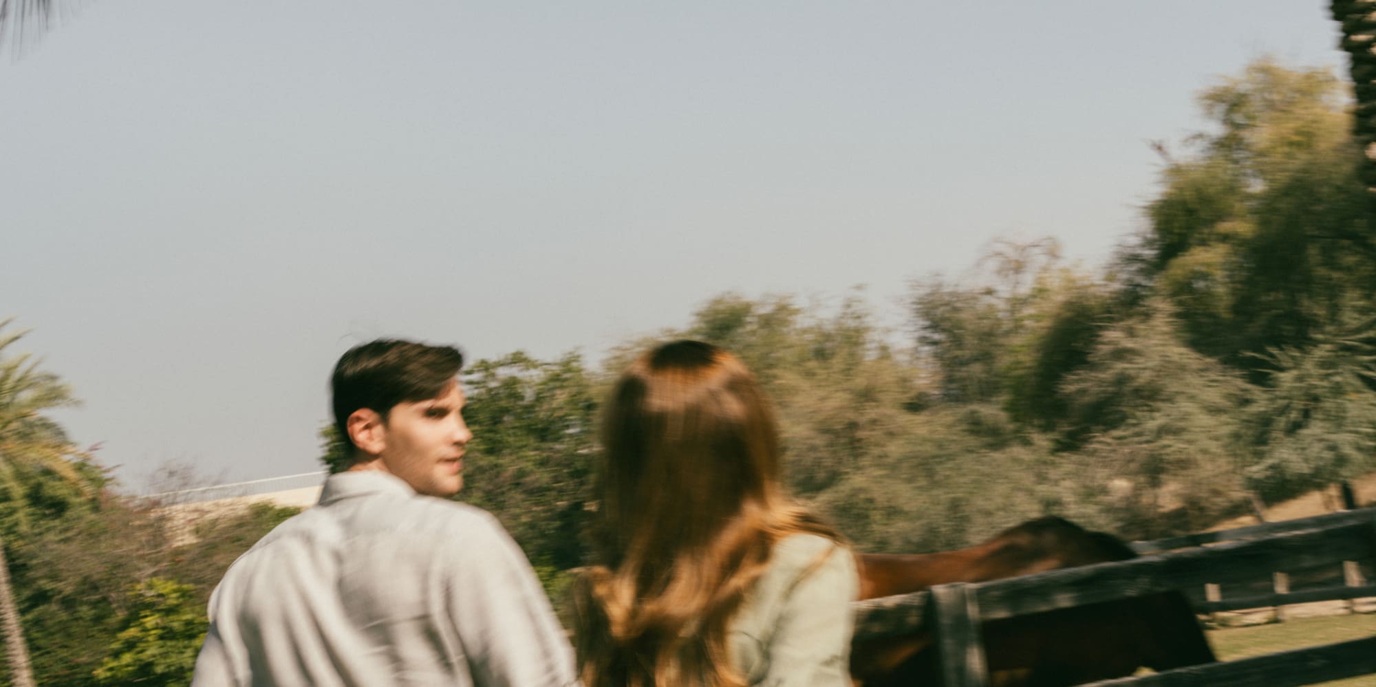 a man and woman walking by a fence and palm trees