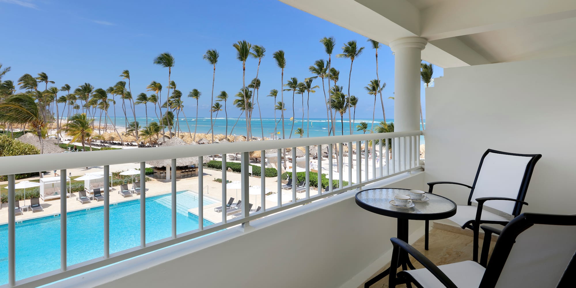 a balcony with chairs and a table and a pool