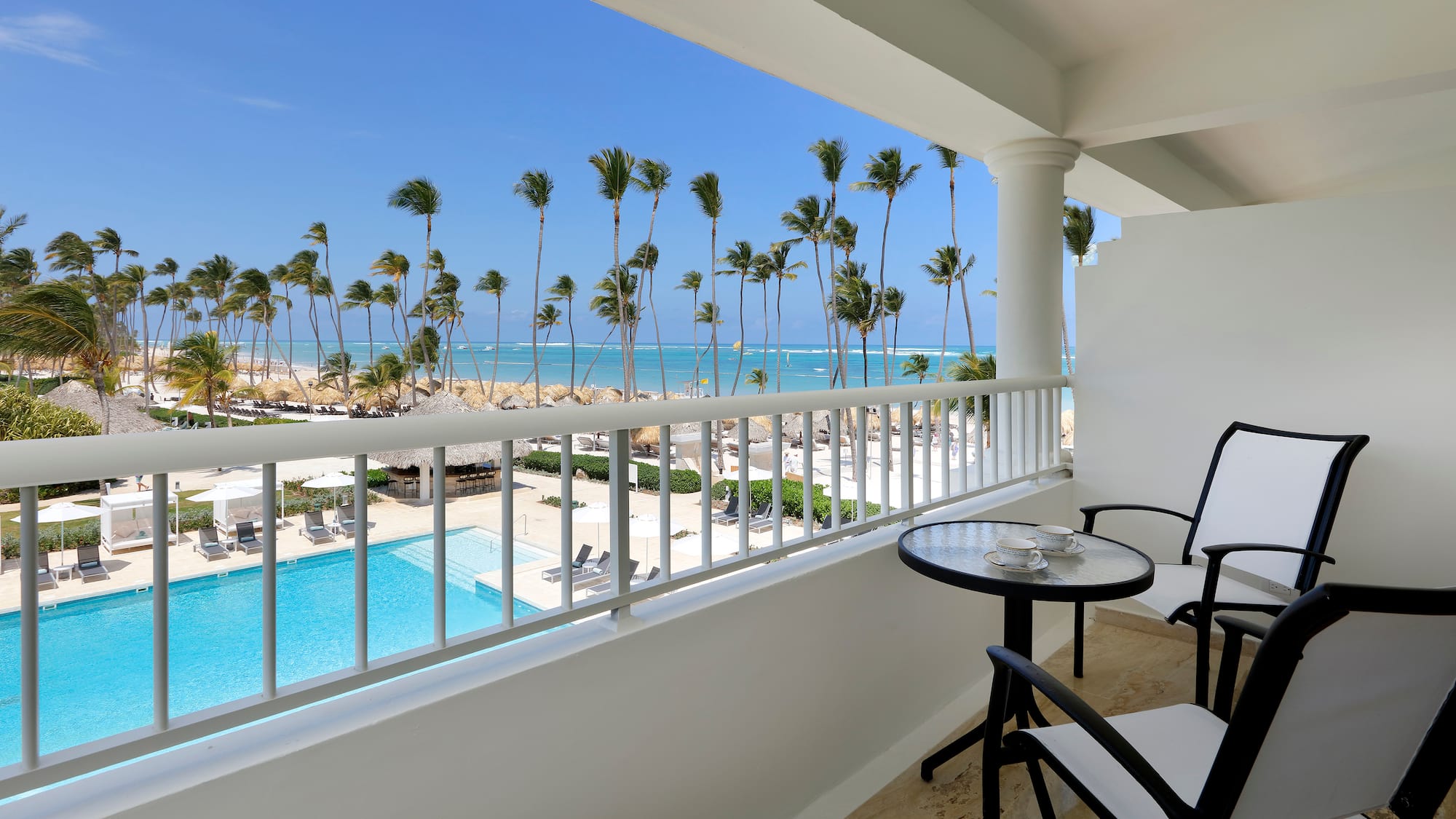 a balcony with chairs and a table and a pool