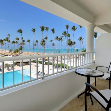 a balcony with chairs and a table and a pool