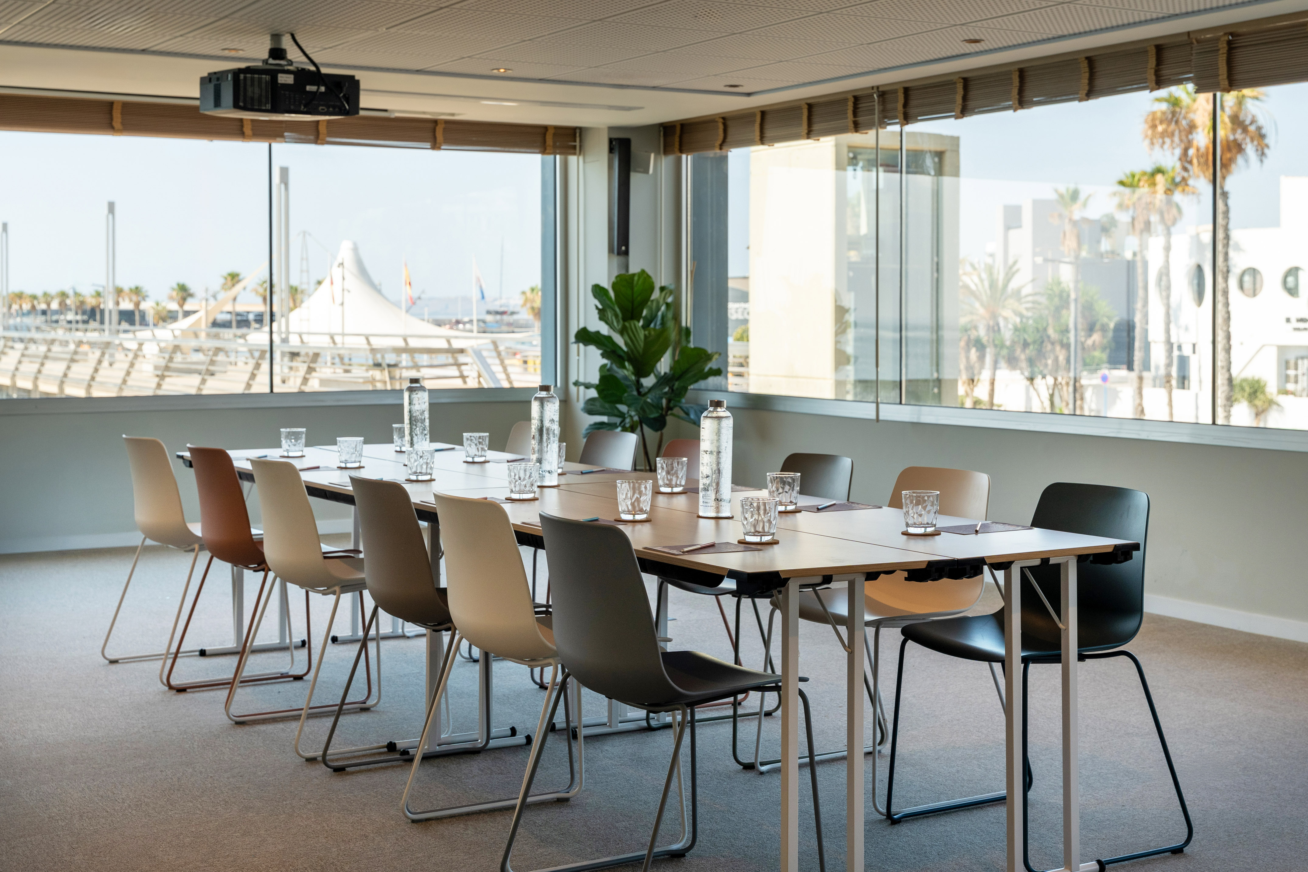 Modern meeting room with long table, projector, and panoramic marina view.