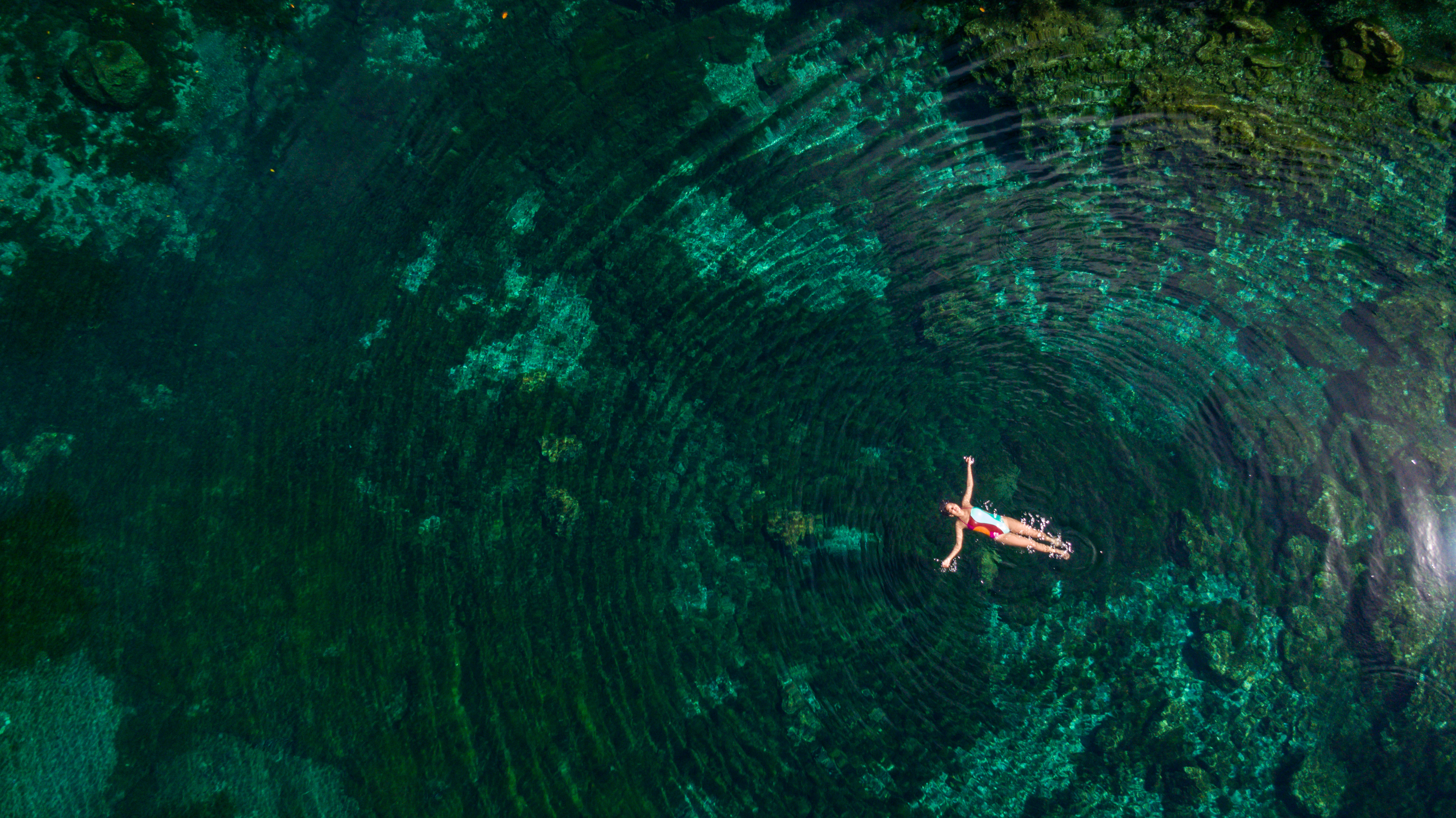 a person swimming in a clear pool.