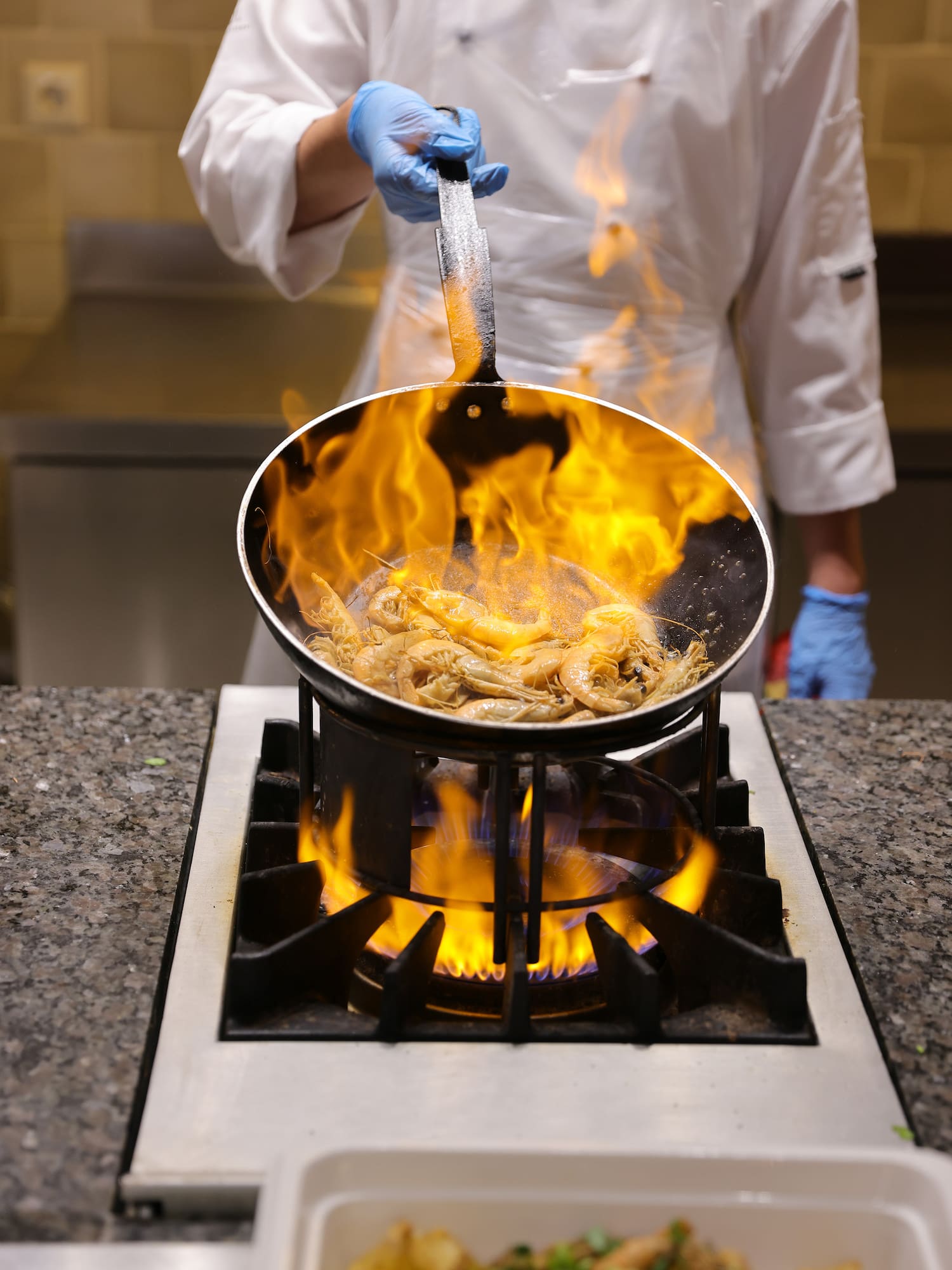a chef cooking food on a pan over a fire