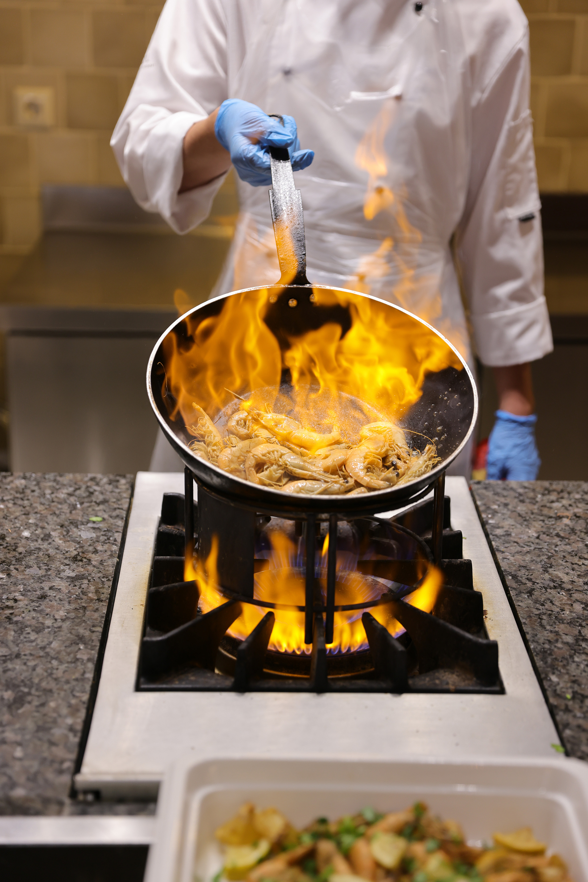 a chef cooking food on a pan over a fire