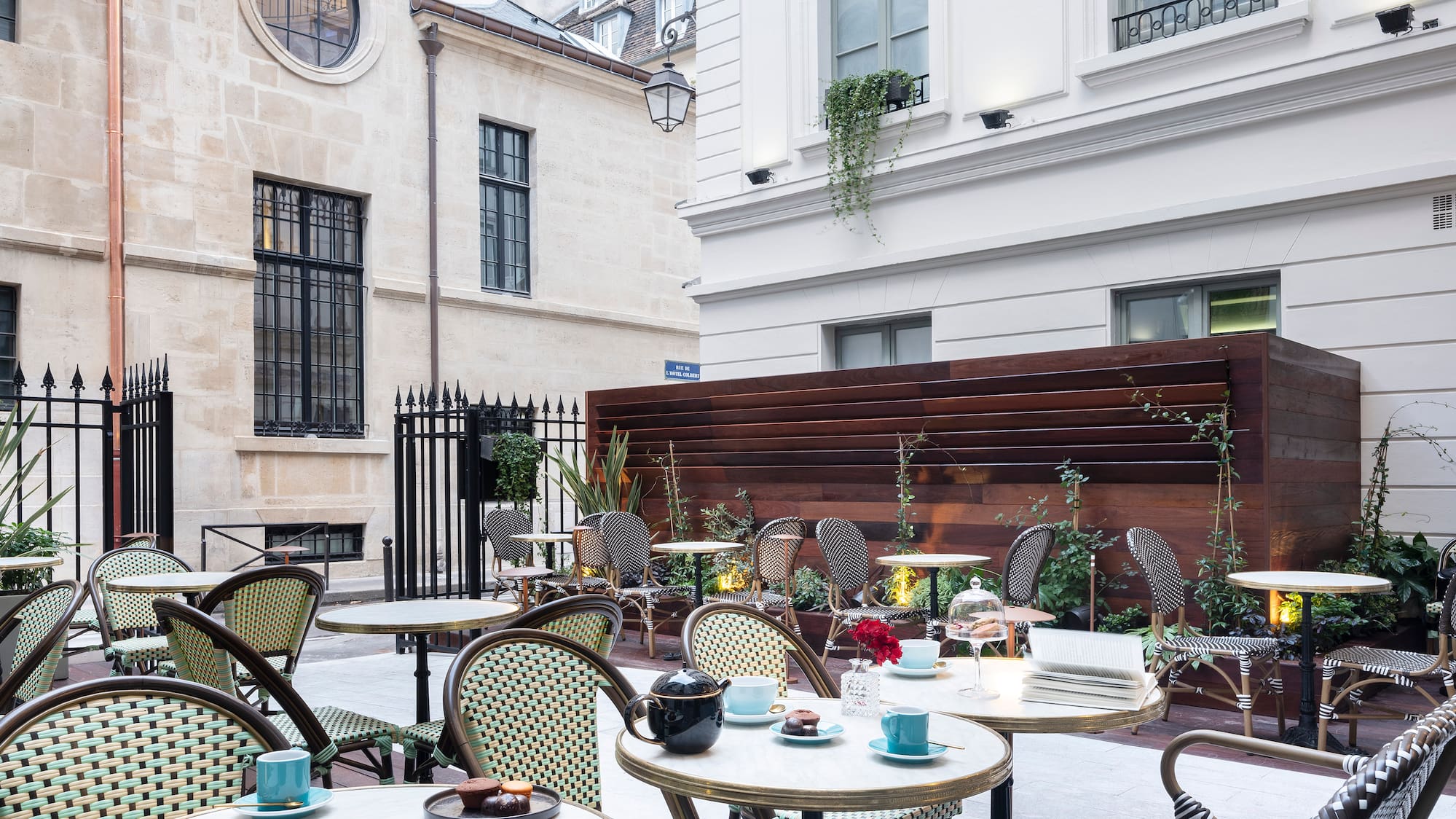 Paris cafe courtyard with bistro chairs, marble tables, pastries, classic buildings.