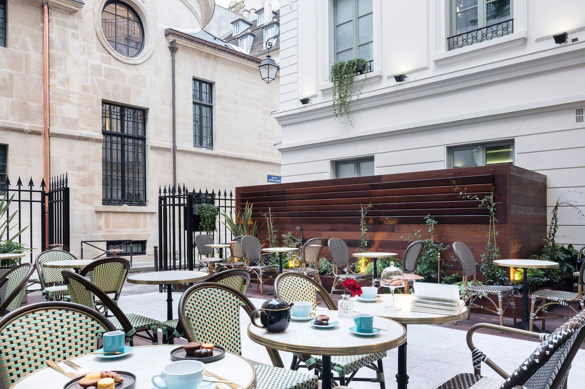 Paris cafe courtyard with bistro chairs, marble tables, pastries, classic buildings.