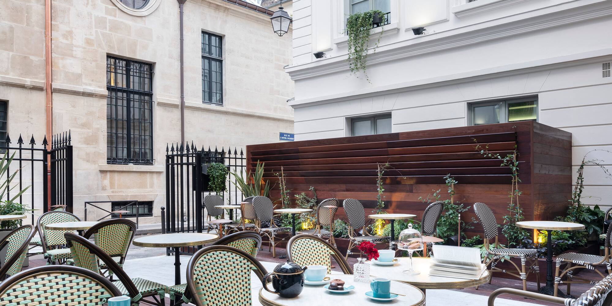 Paris cafe courtyard with bistro chairs, marble tables, pastries, classic buildings.