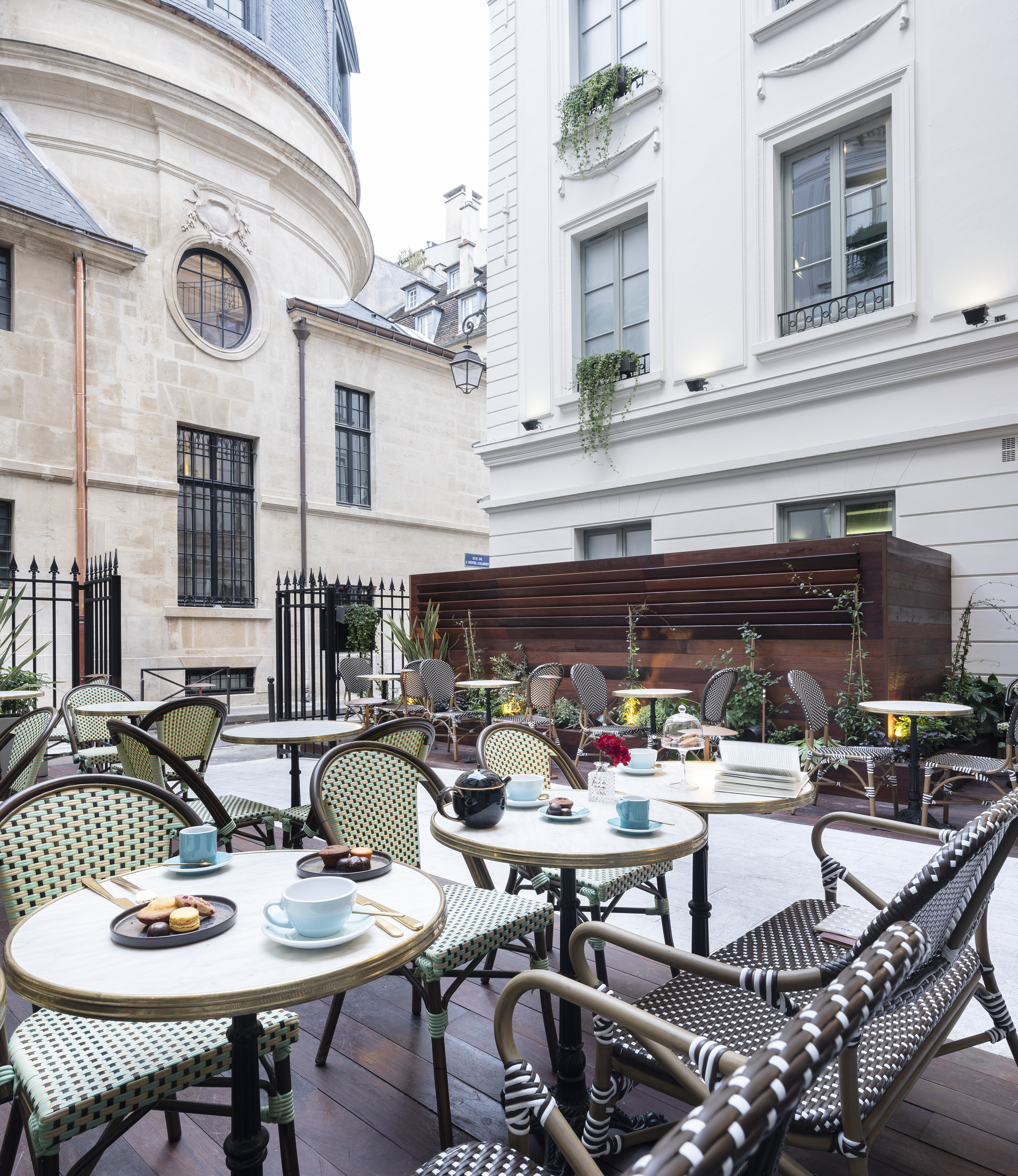 Paris cafe courtyard with bistro chairs, marble tables, pastries, classic buildings.