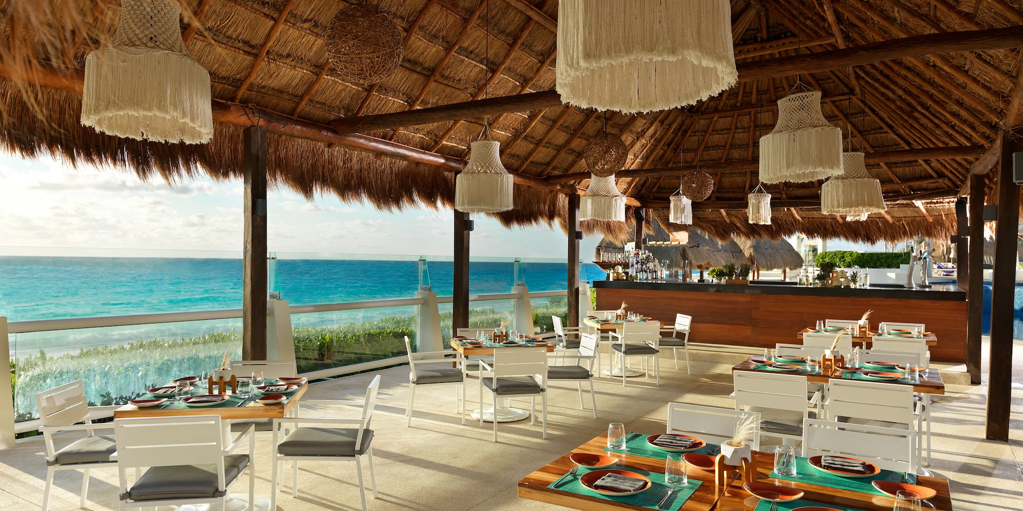 a restaurant with a thatched roof and a large body of water