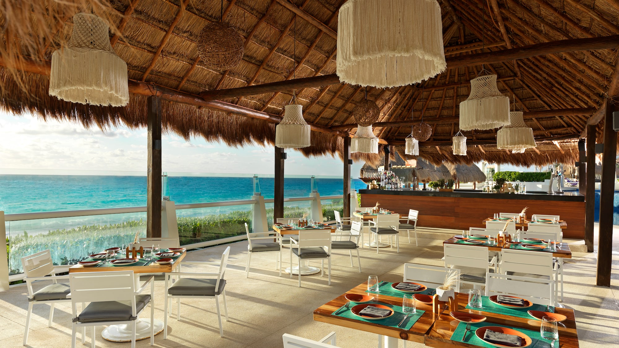 a restaurant with a thatched roof and a large body of water