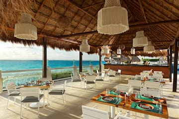 a restaurant with a thatched roof and a large body of water