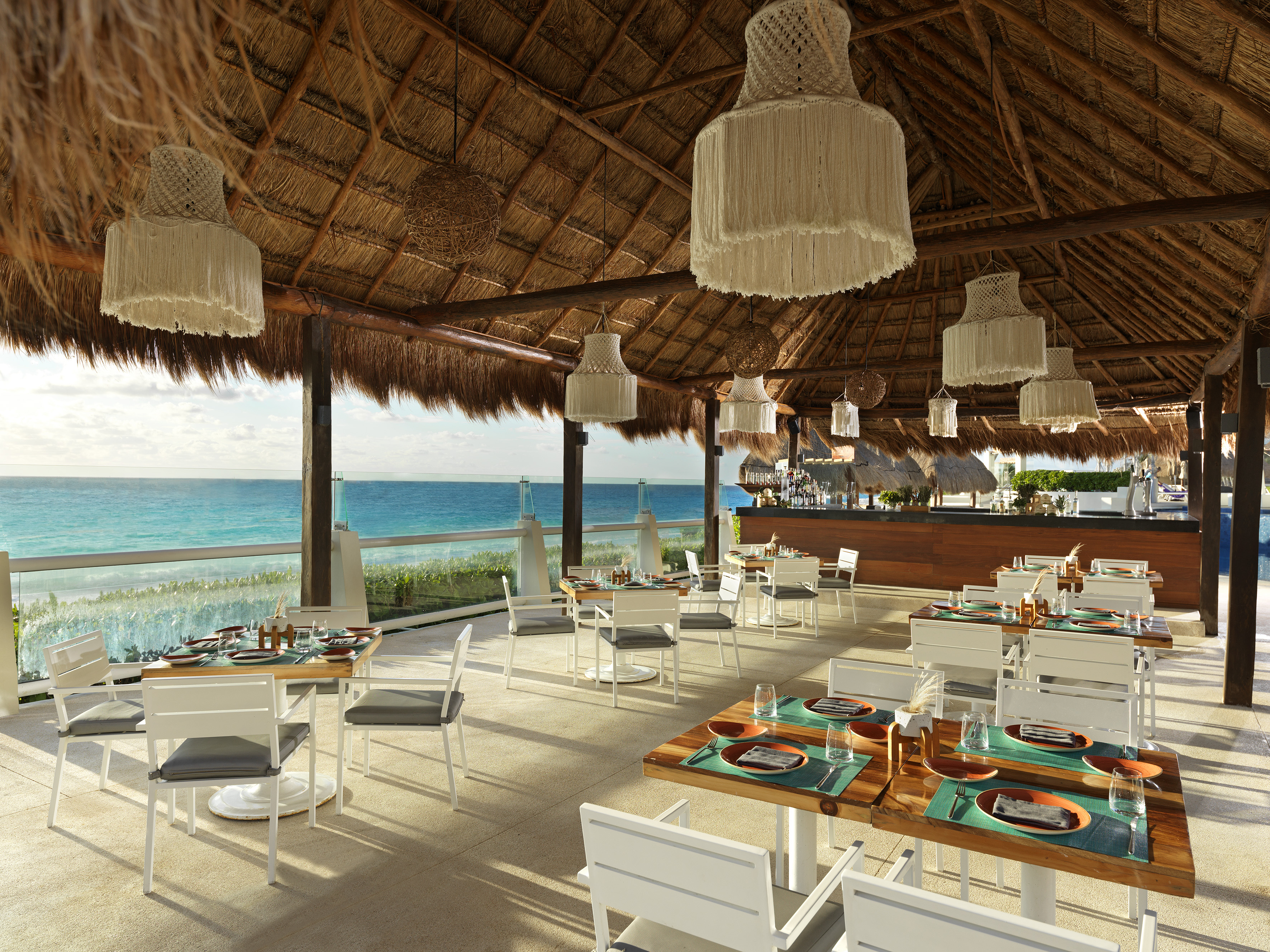 a restaurant with a thatched roof and a large body of water