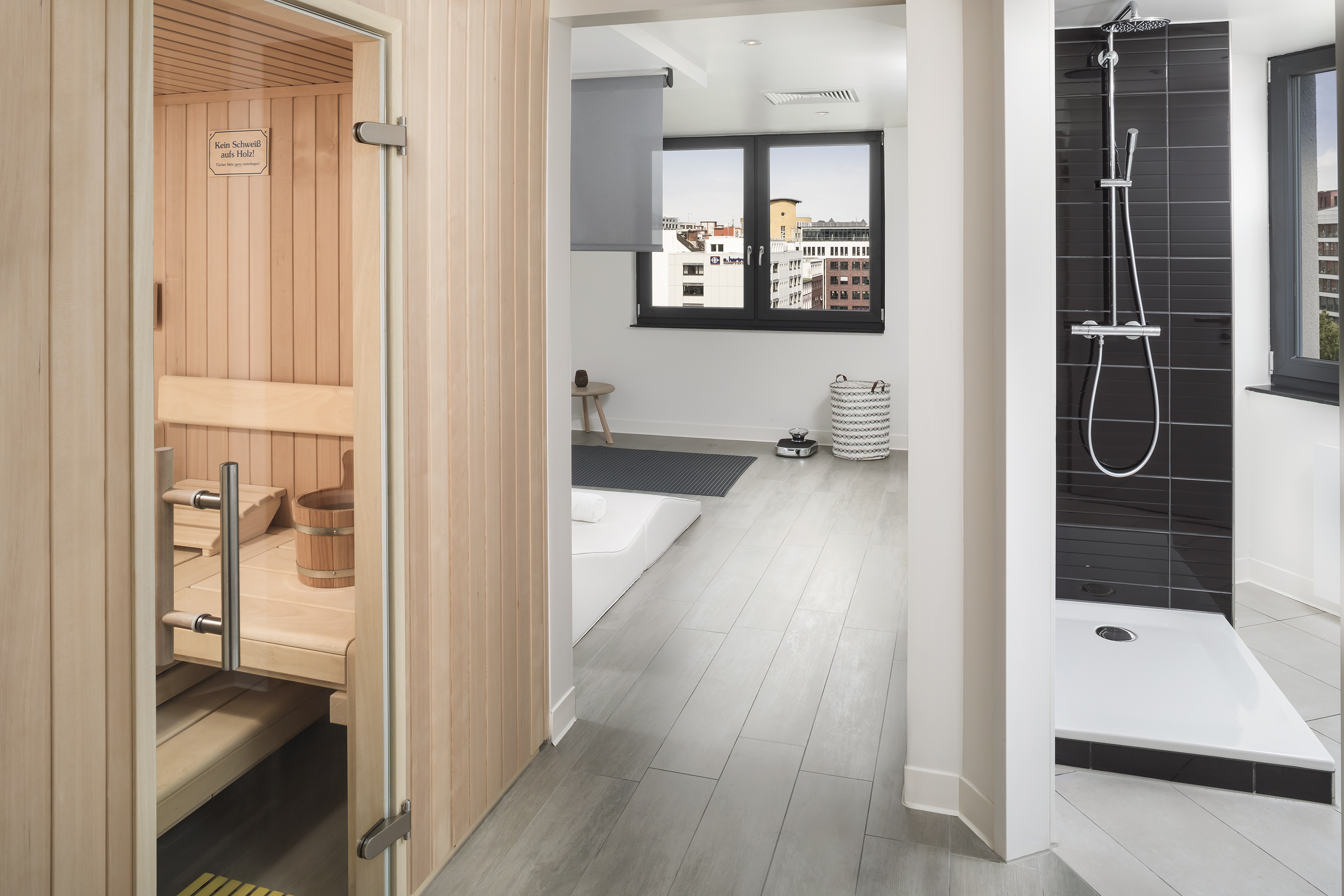 Modern wellness space with private wooden sauna, walk-in shower, and city view.