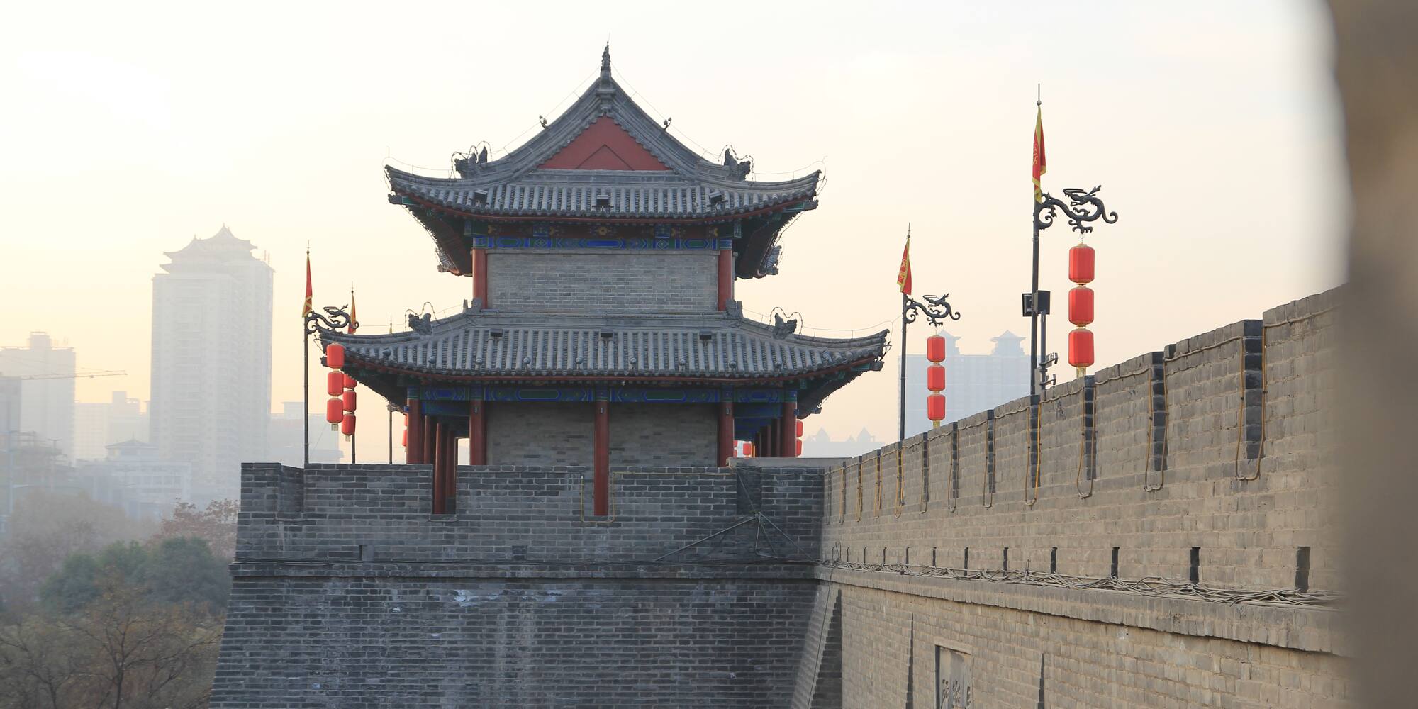 a tower with red lanterns and flags on top of a stone wall