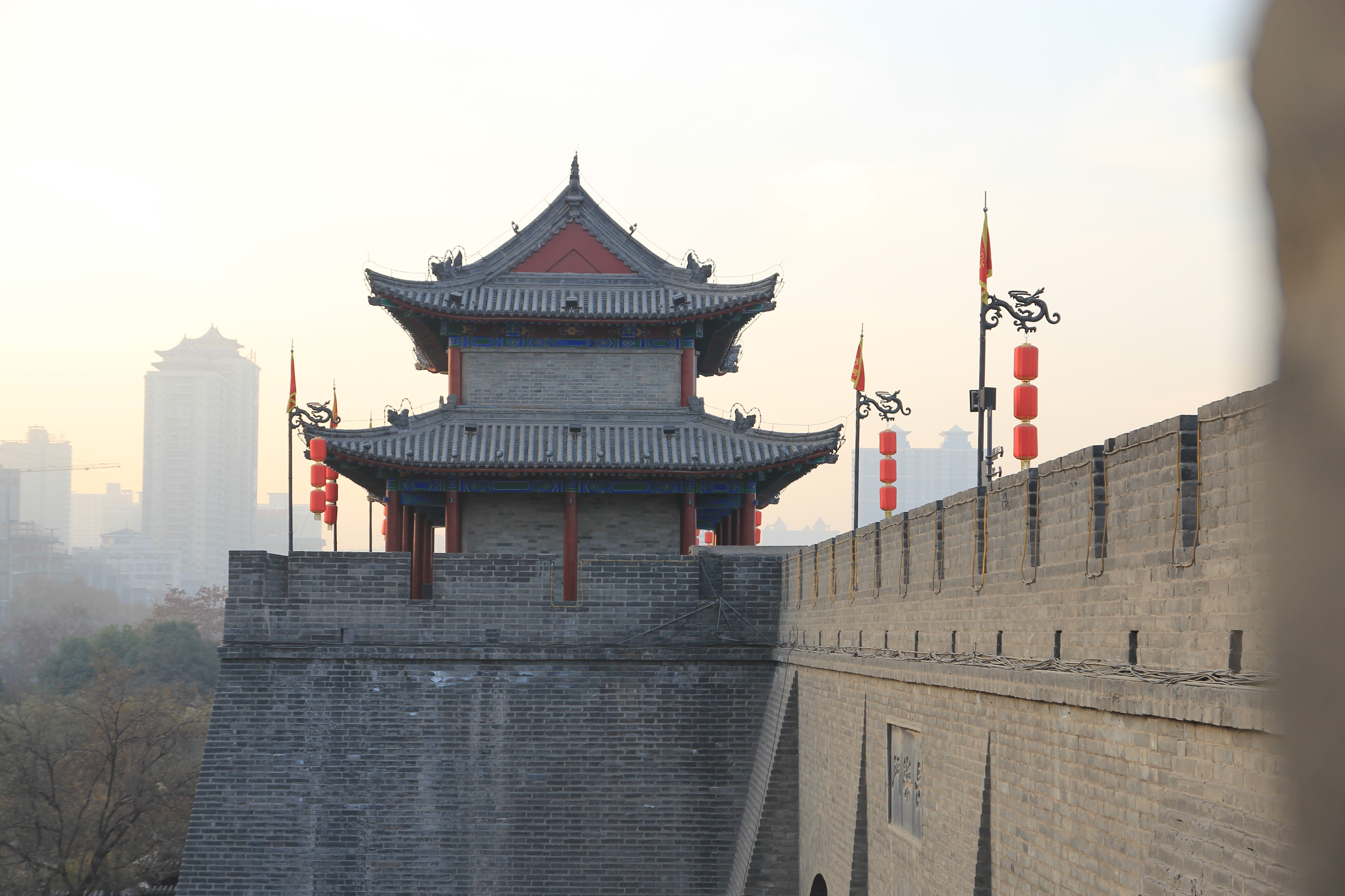 a tower with red lanterns and flags on top of a stone wall