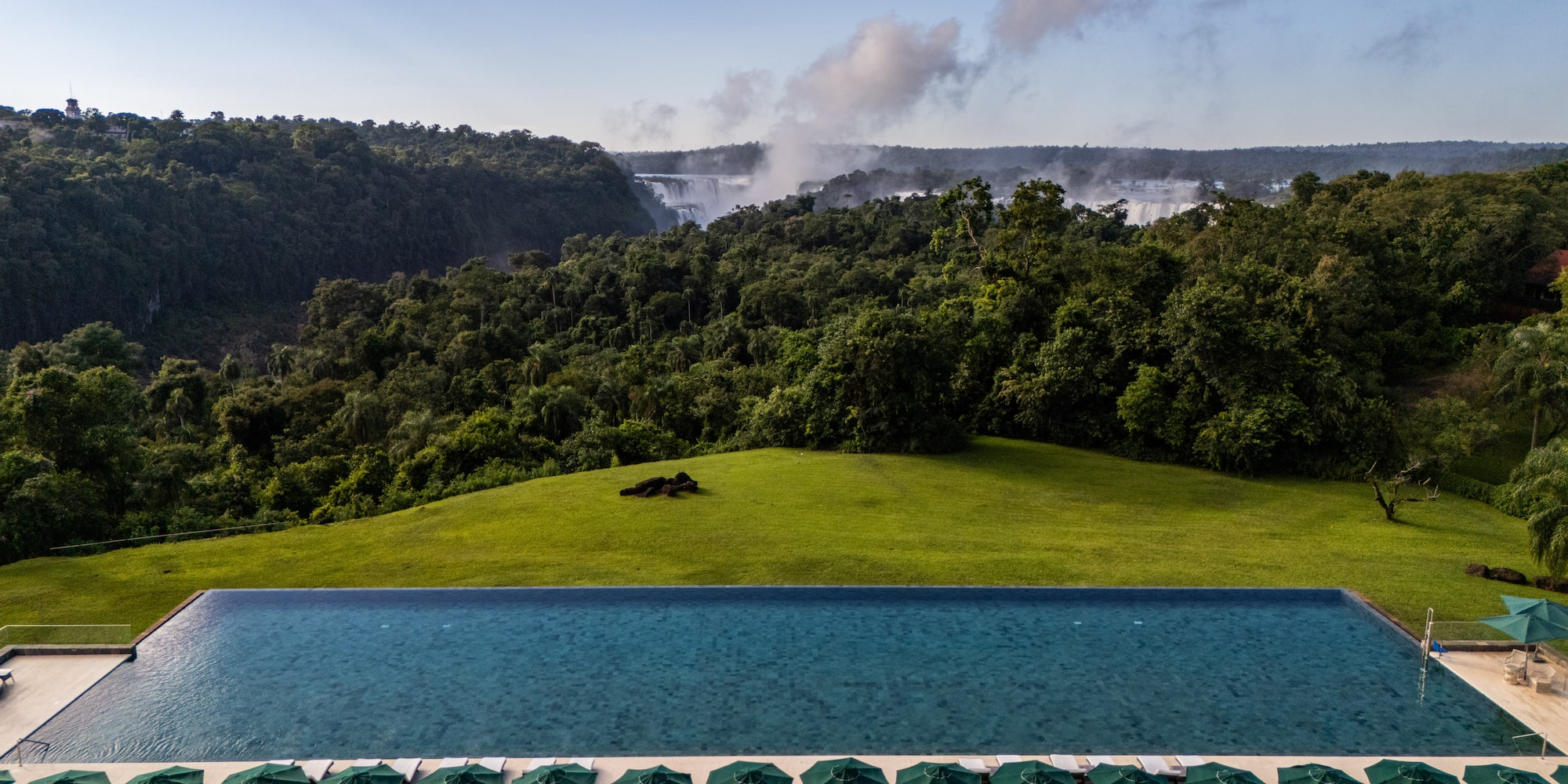 a pool with umbrellas and a waterfall in the background