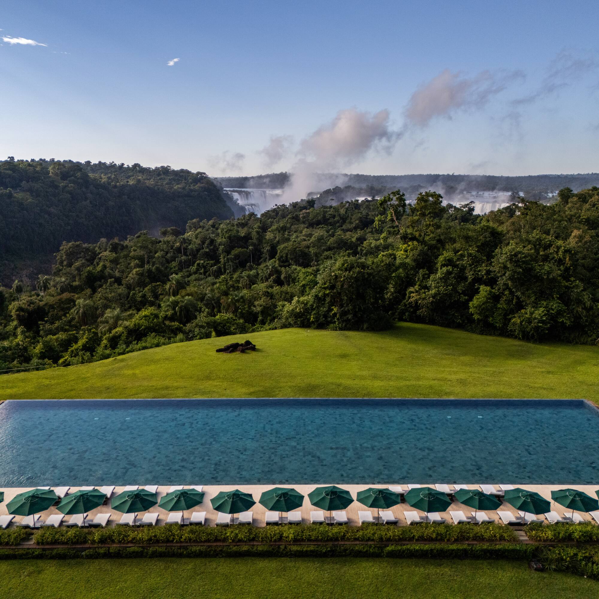 a pool with umbrellas and a waterfall in the background