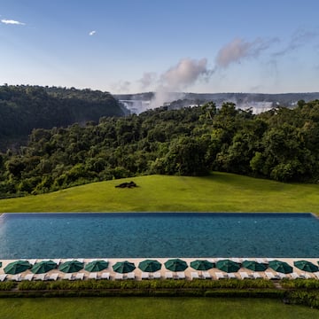 a pool with umbrellas and a waterfall in the background