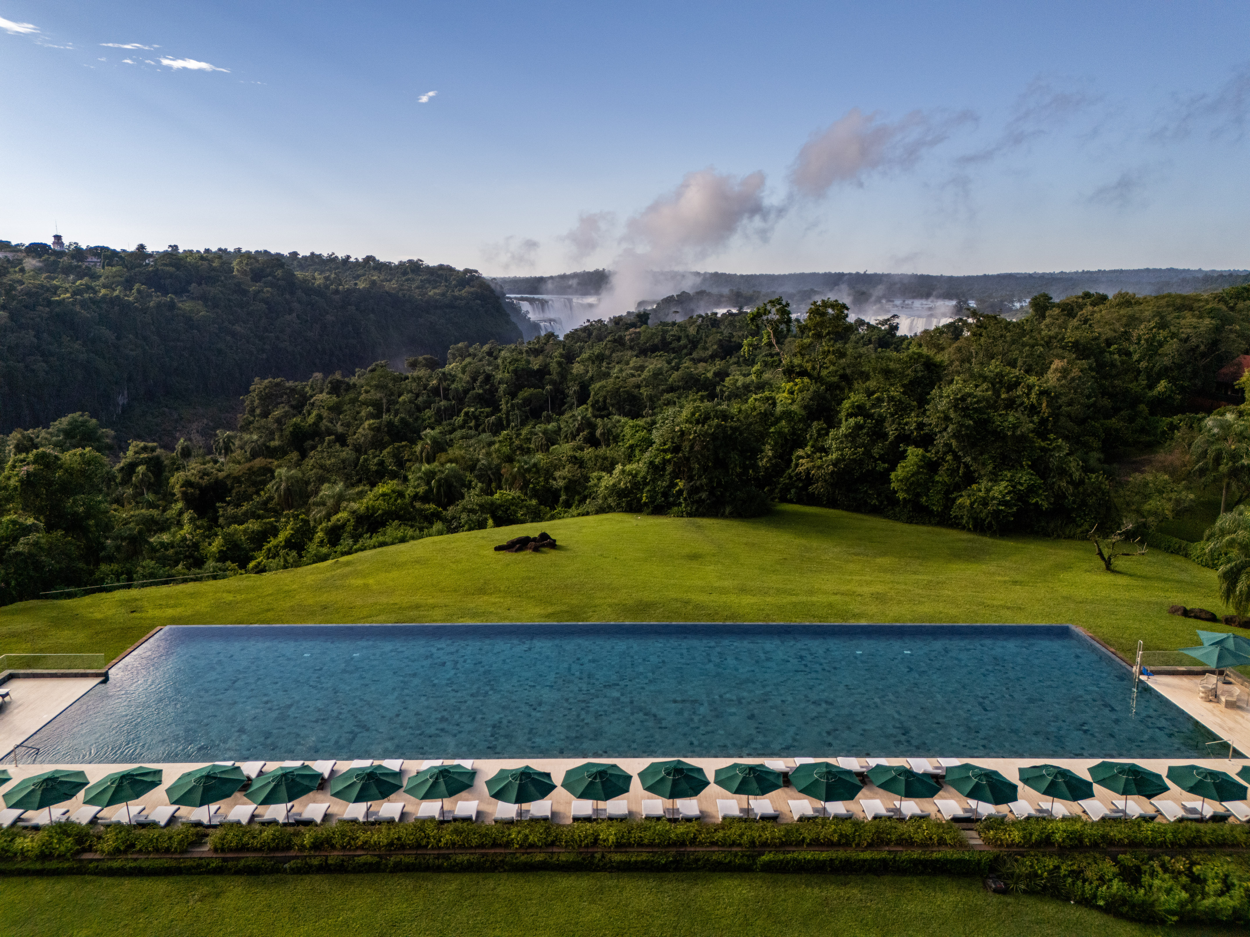 a pool with umbrellas and a waterfall in the background