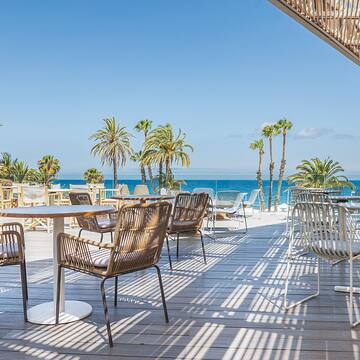 a patio with tables and chairs and palm trees