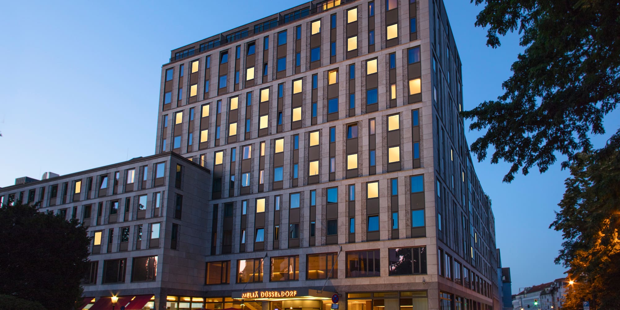 Meliá Düsseldorf hotel, modern building with illuminated windows at night.