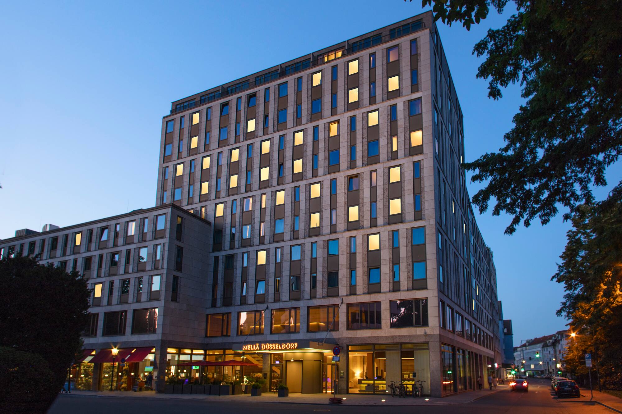 Meliá Düsseldorf hotel, modern building with illuminated windows at night.