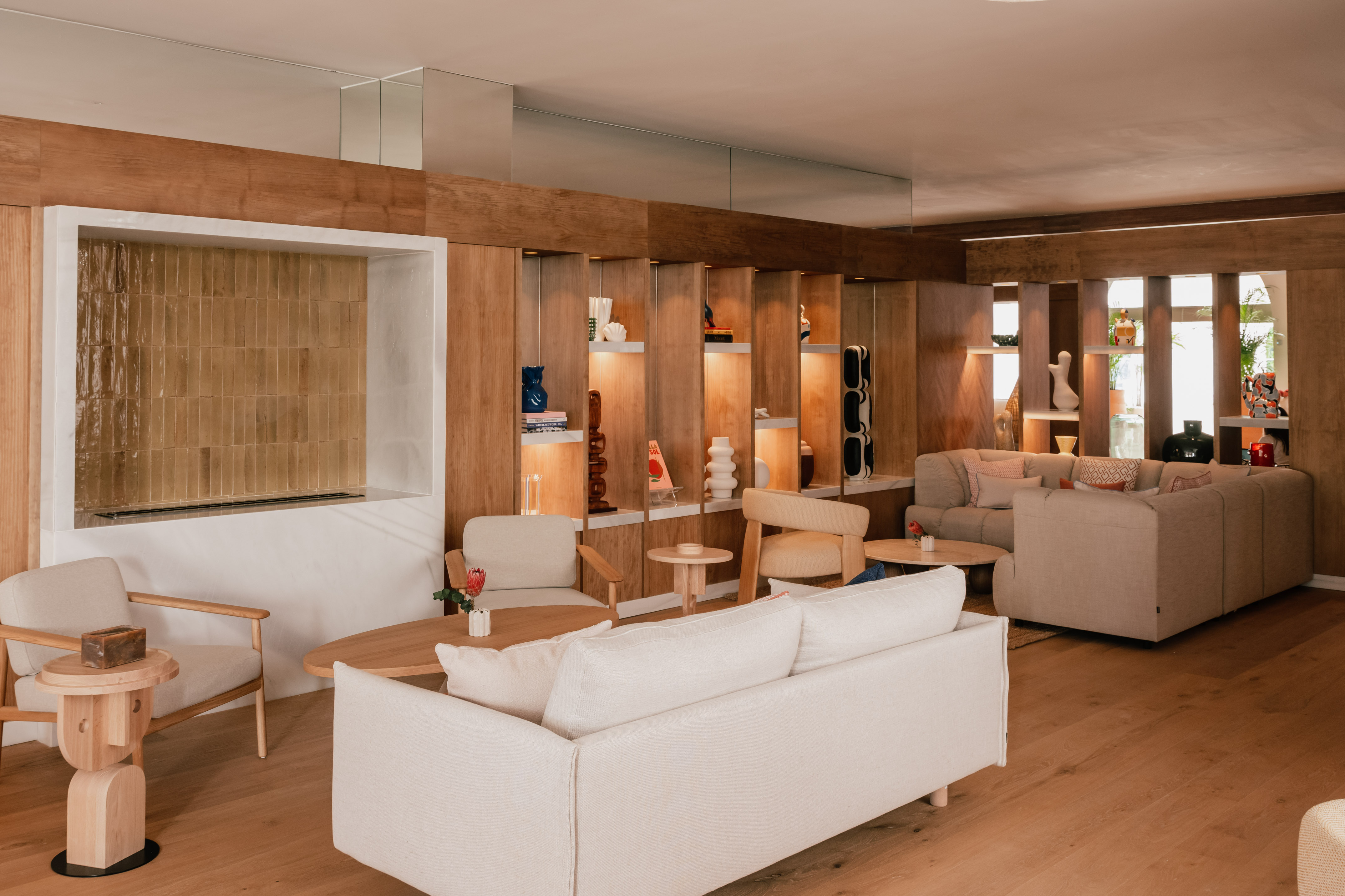 Stylish lounge with wood paneling, decorative shelves, and neutral seating.