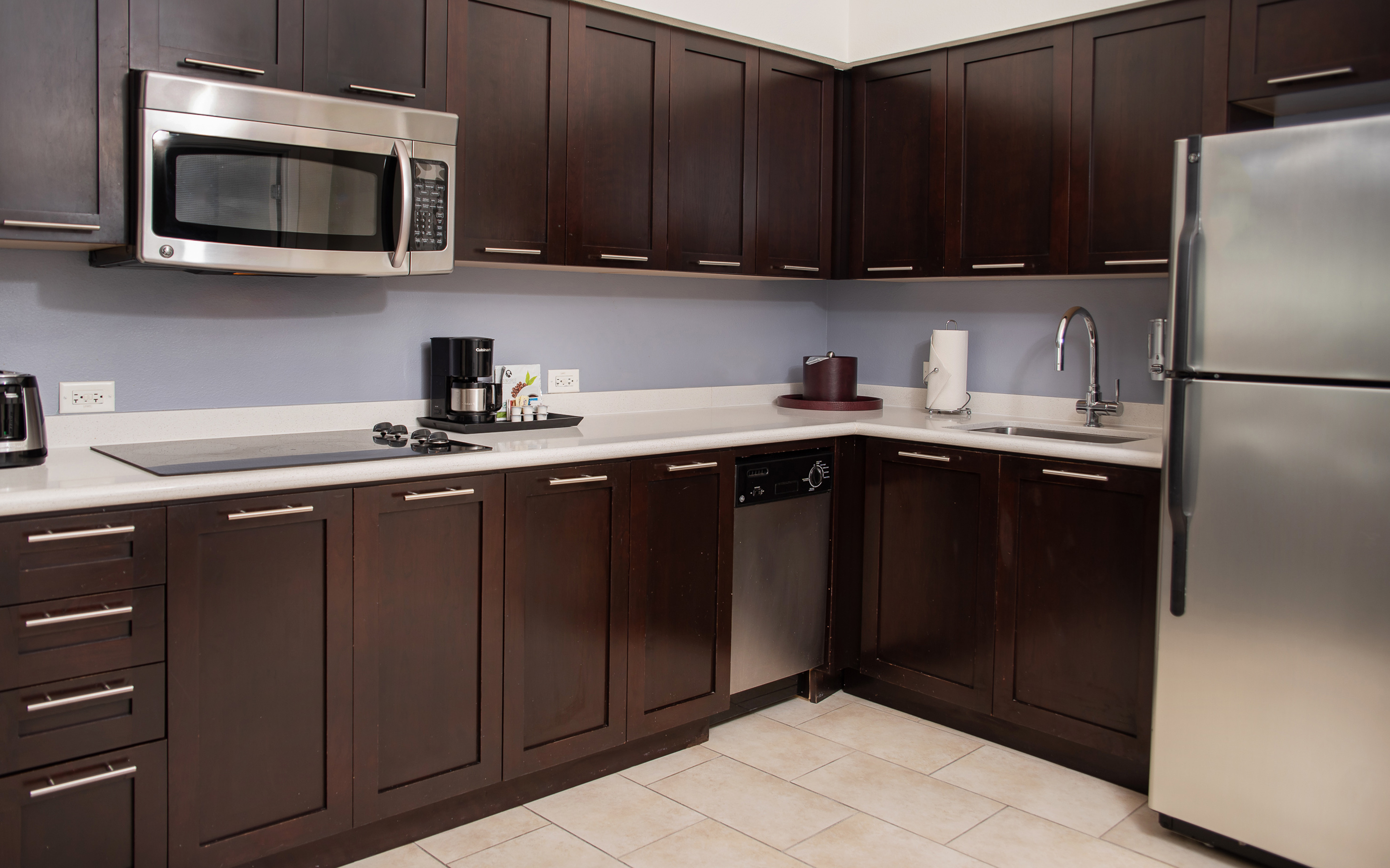 Modern kitchen: dark wood cabinets, stainless steel microwave, fridge, cooktop.